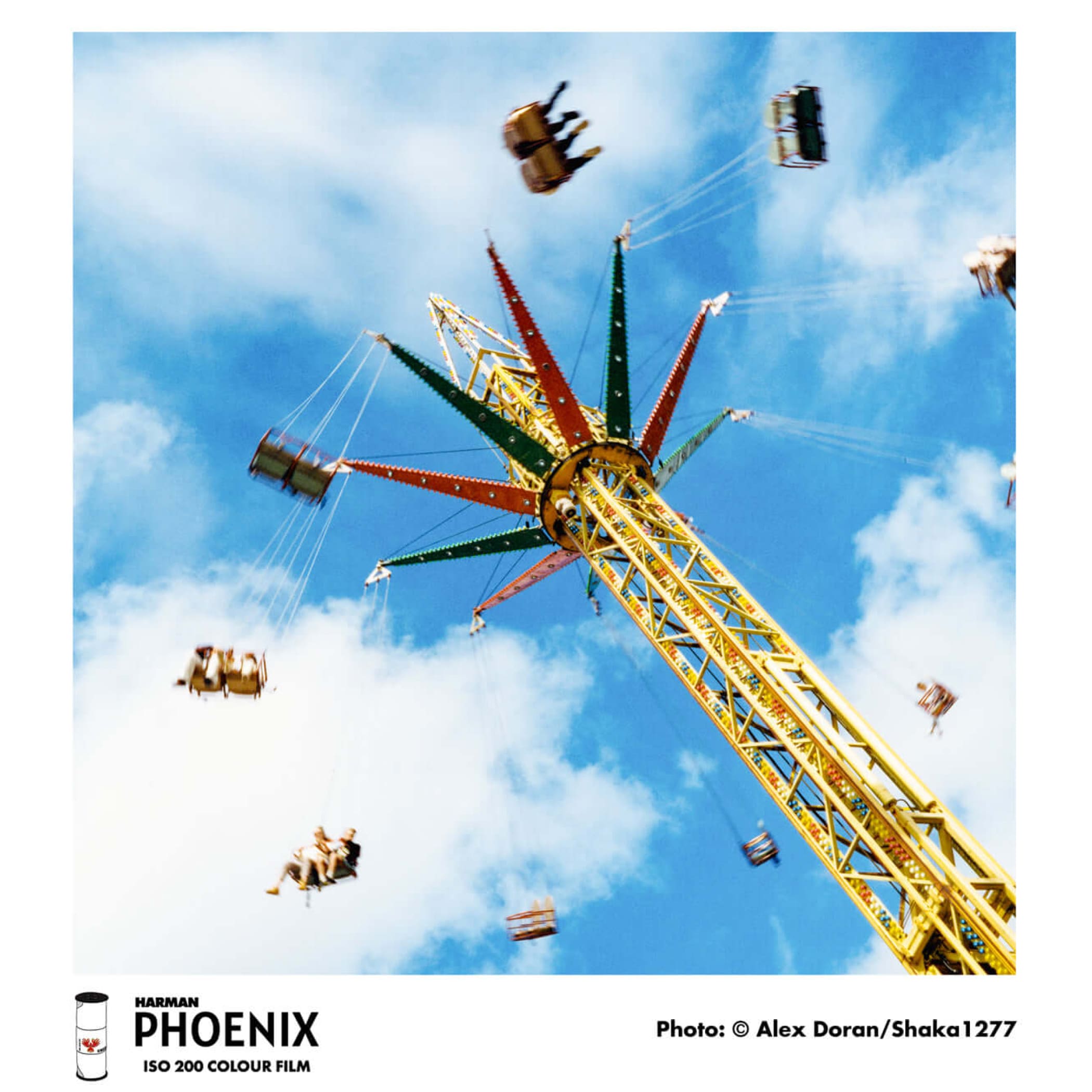 A vibrant yellow and green star-shaped amusement park ride with suspended seats against a bright blue sky.