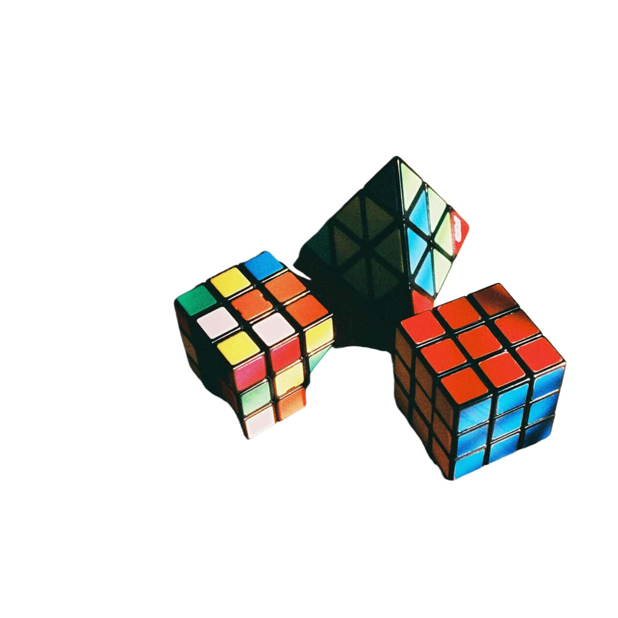 Three colorful rubik’s cubes, one solved and two partially scrambled, rest on a warm-toned wooden surface.