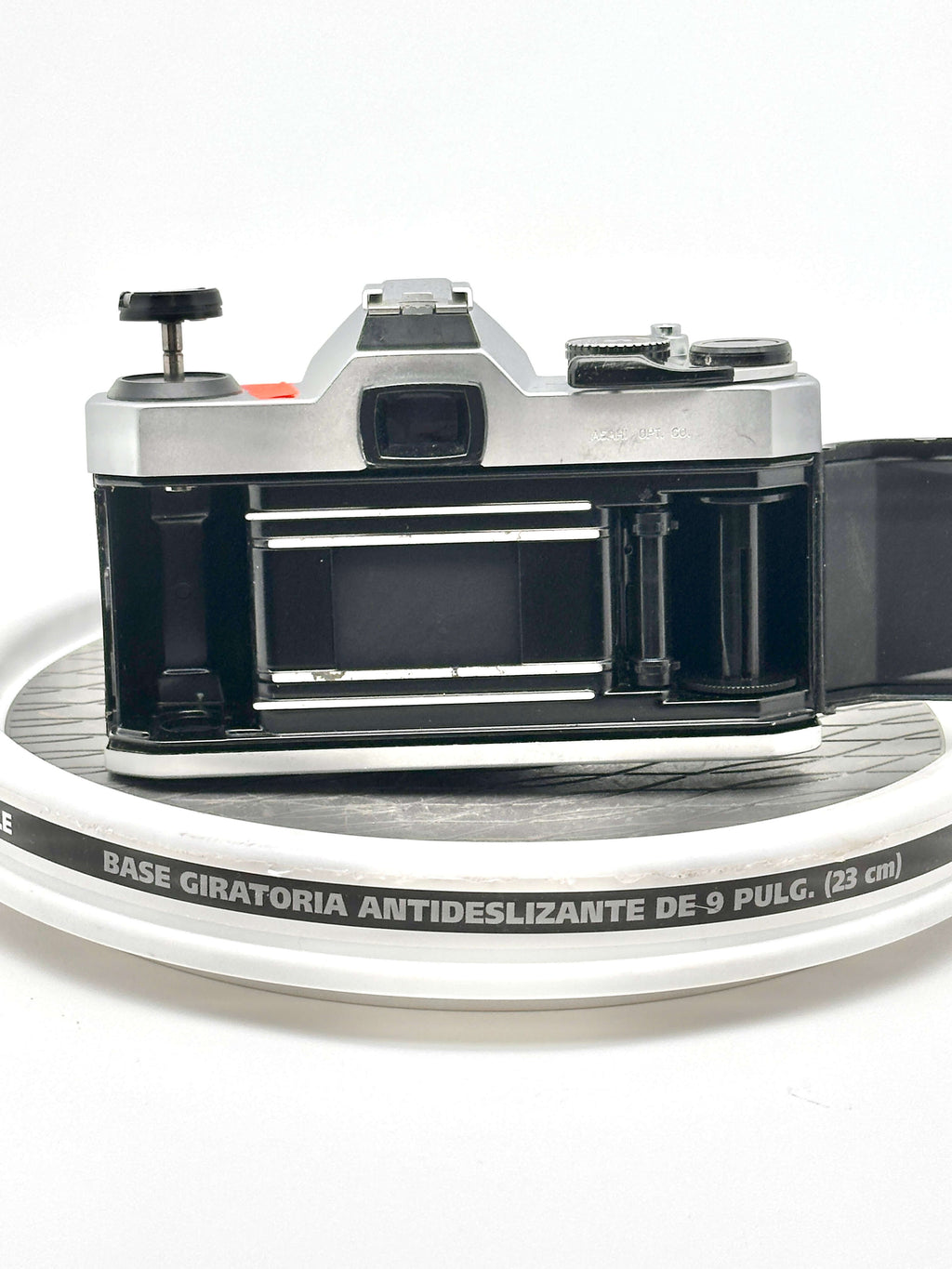 Pentax K1000 black 35mm film camera rear view on a round surface, showcasing its empty film compartment.