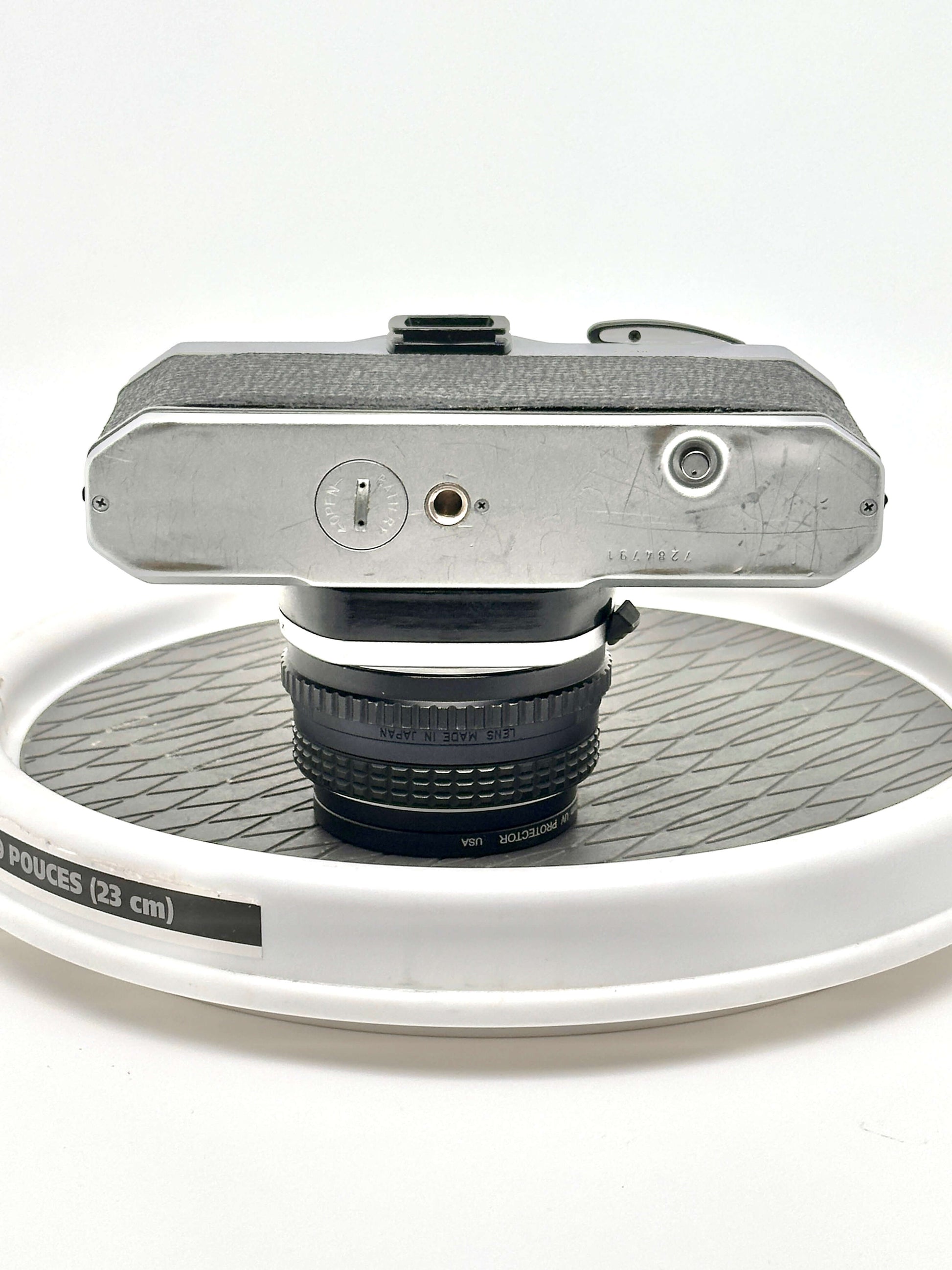 Bottom view of a Pentax K1000 black 35mm film camera showcasing its connection ports and 50mm lens.