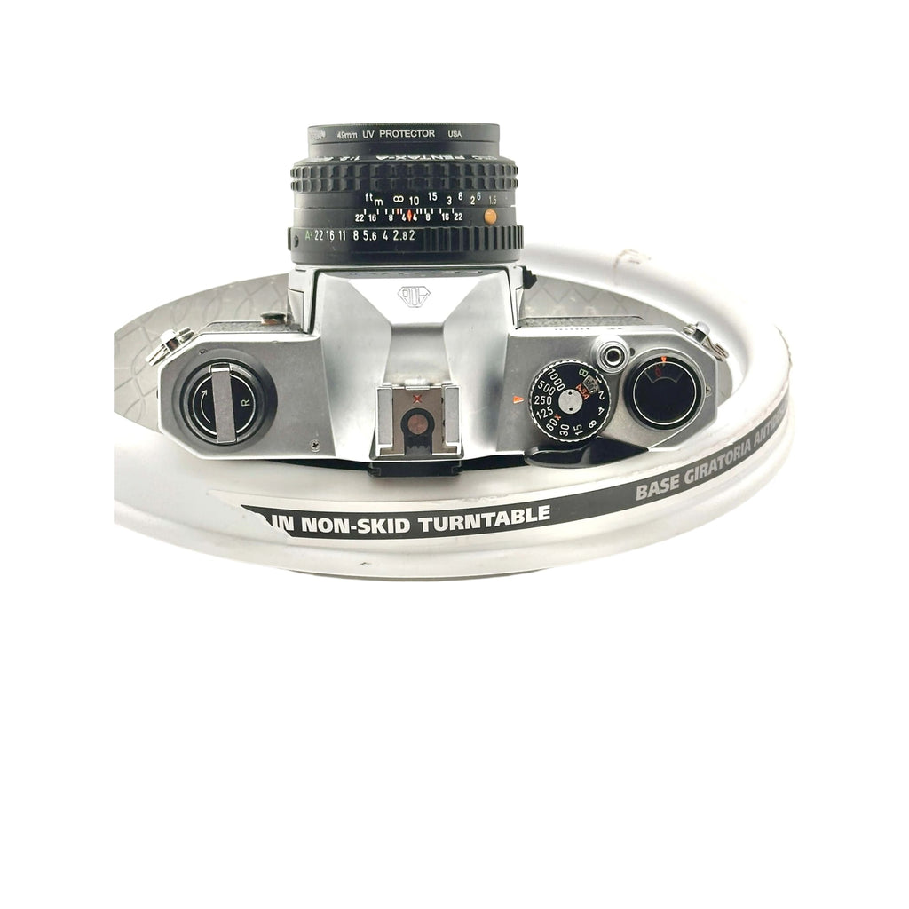 Silver-bodied canon ae-1 film camera with a black 40mm uv protector lens mounted on top.