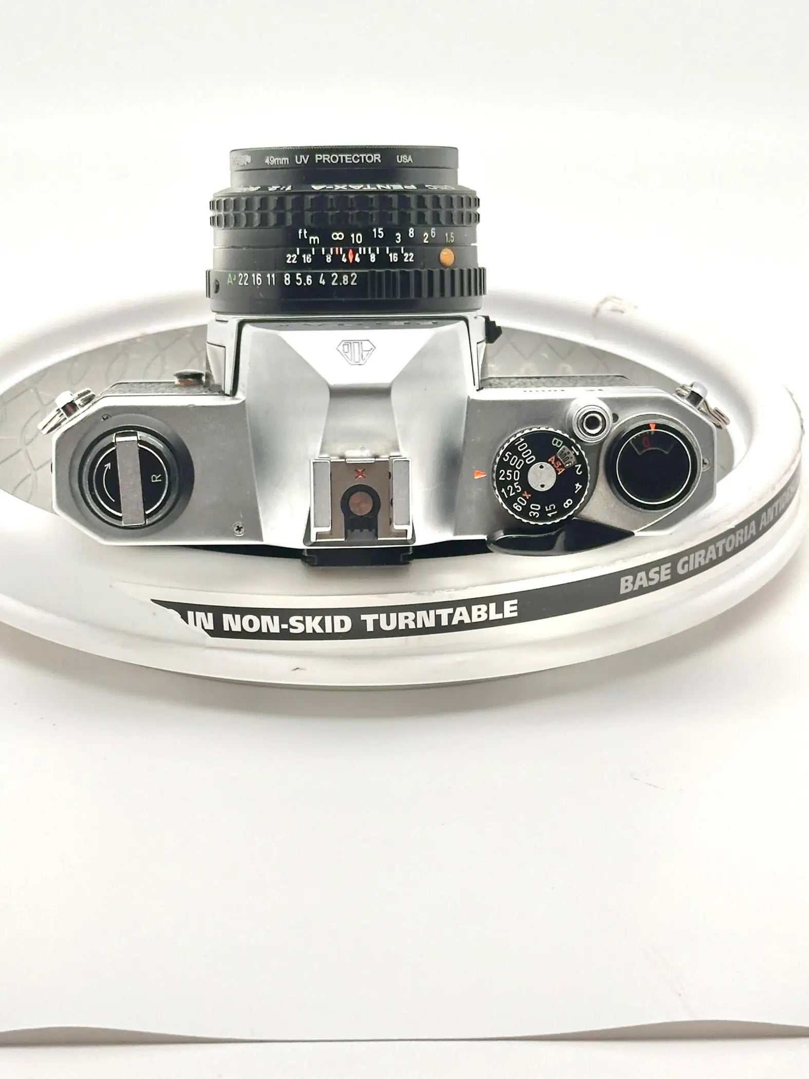 Silver-bodied canon ae-1 film camera with a black 40mm uv protector lens mounted on top.