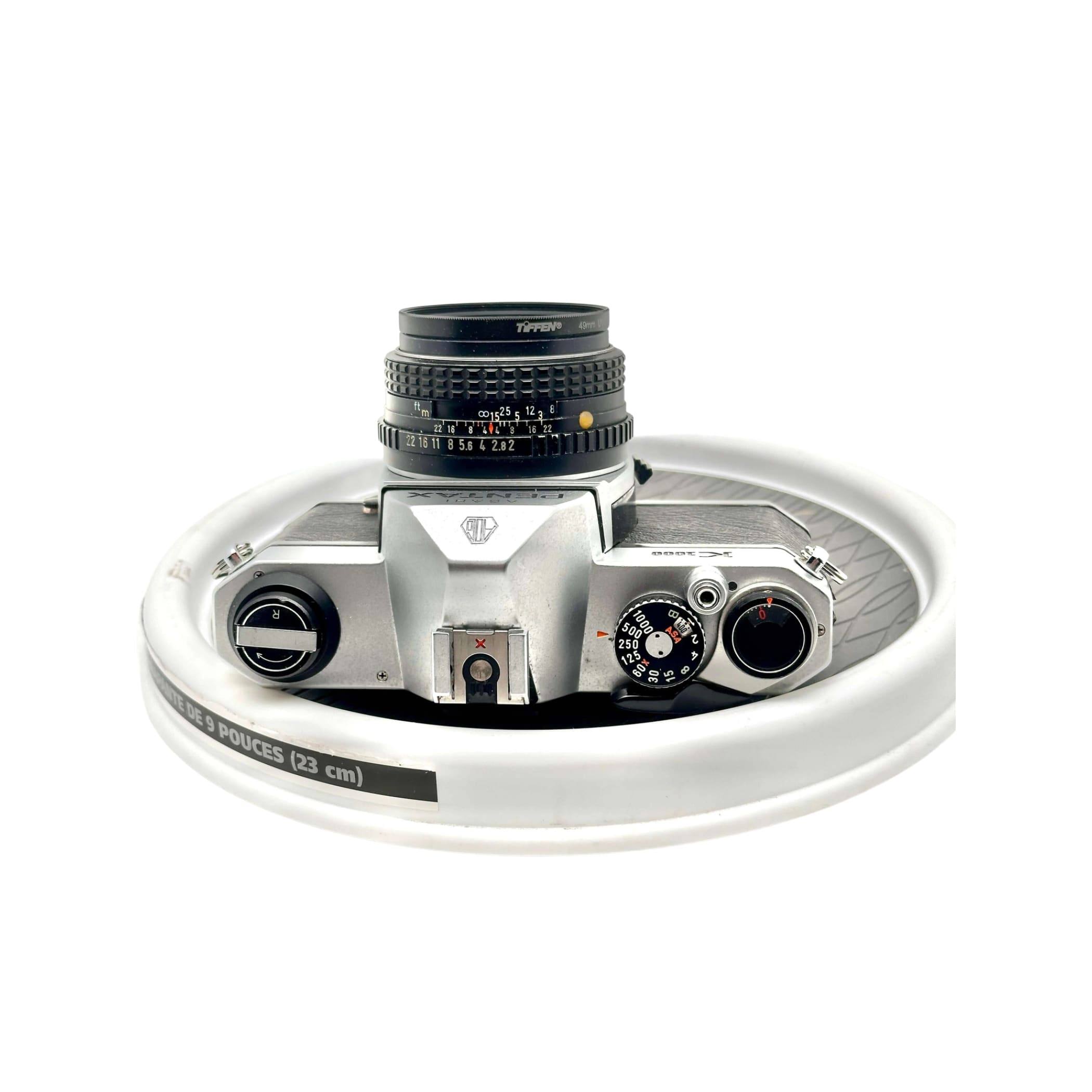 Silver-bodied canon ae-1 film camera with a black topcon lens mounted on top.