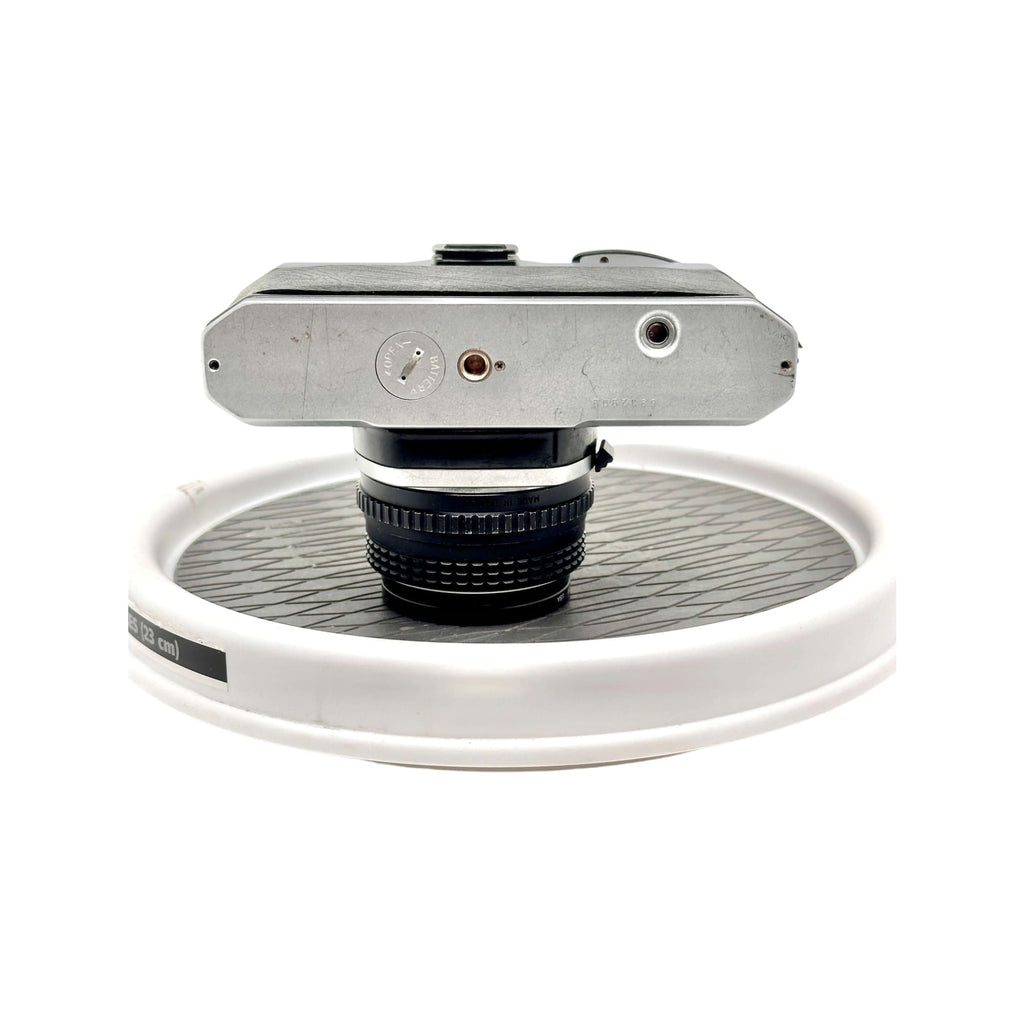 Silver-bodied nikon fm2 film camera with a black lens mounted on top.