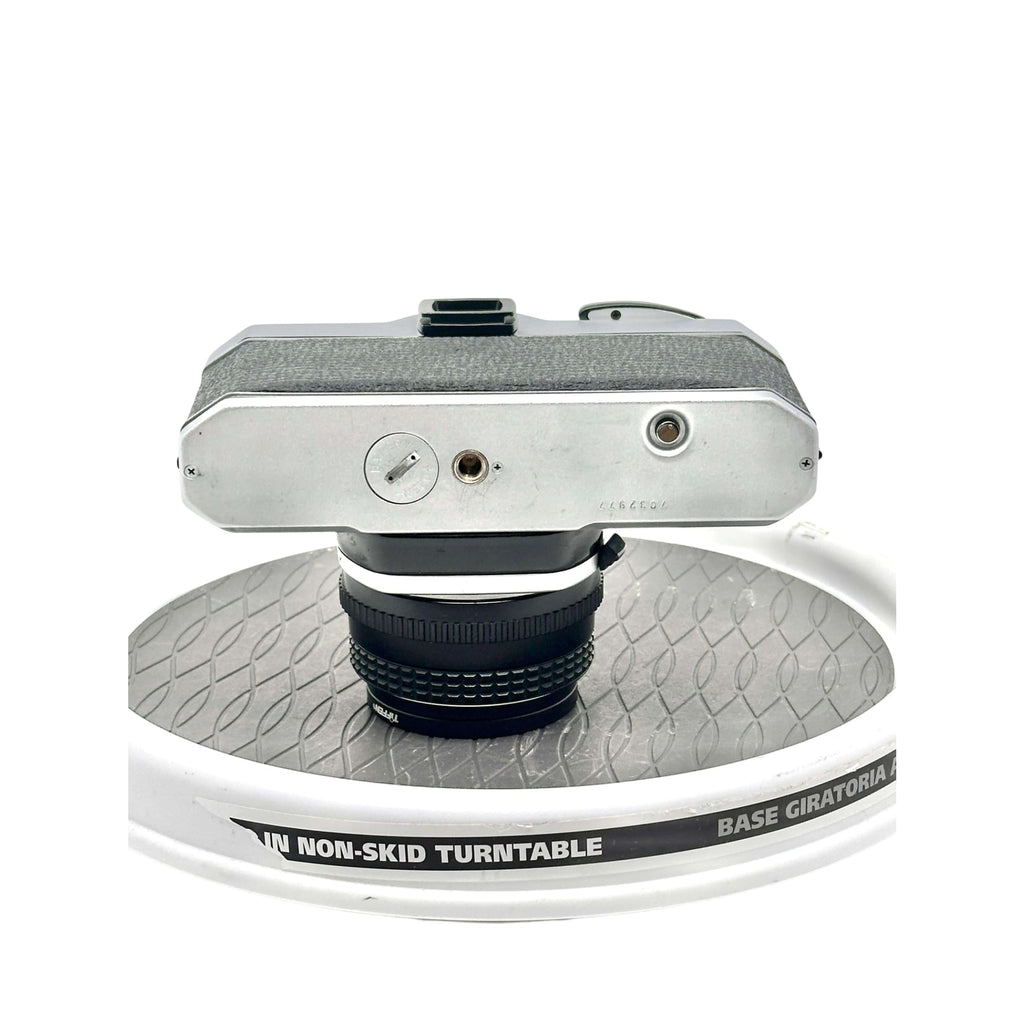 Silver-bodied vintage camera with textured grip and black lens mounted on a turntable.