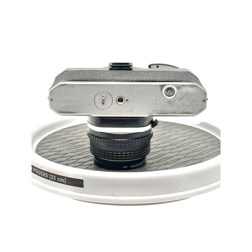 Silver-bodied vintage camera with textured grip and a black lens mounted on top.