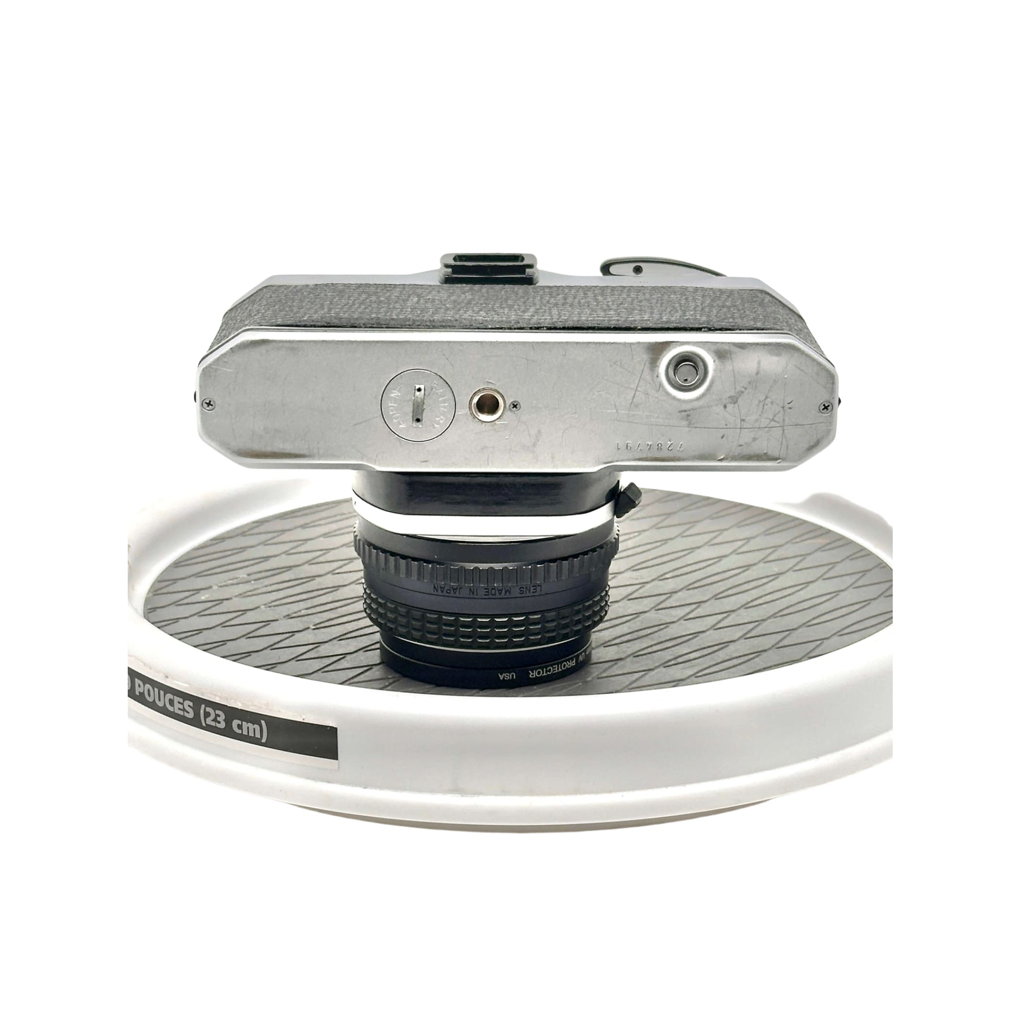 Silver-bodied vintage camera with textured grip and a black lens mounted on top.