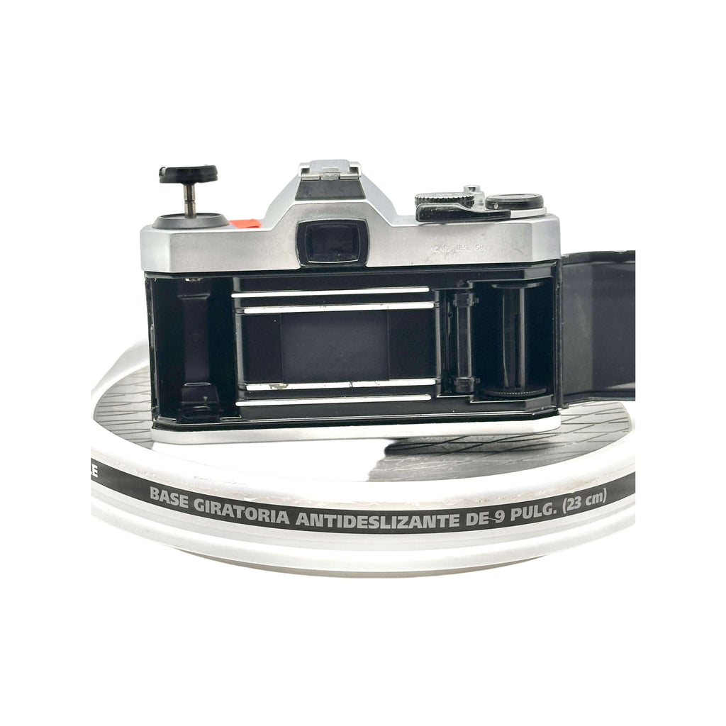 Silver and black vintage film camera with a metallic body, exposed shutter mechanism, and visible lens mount.