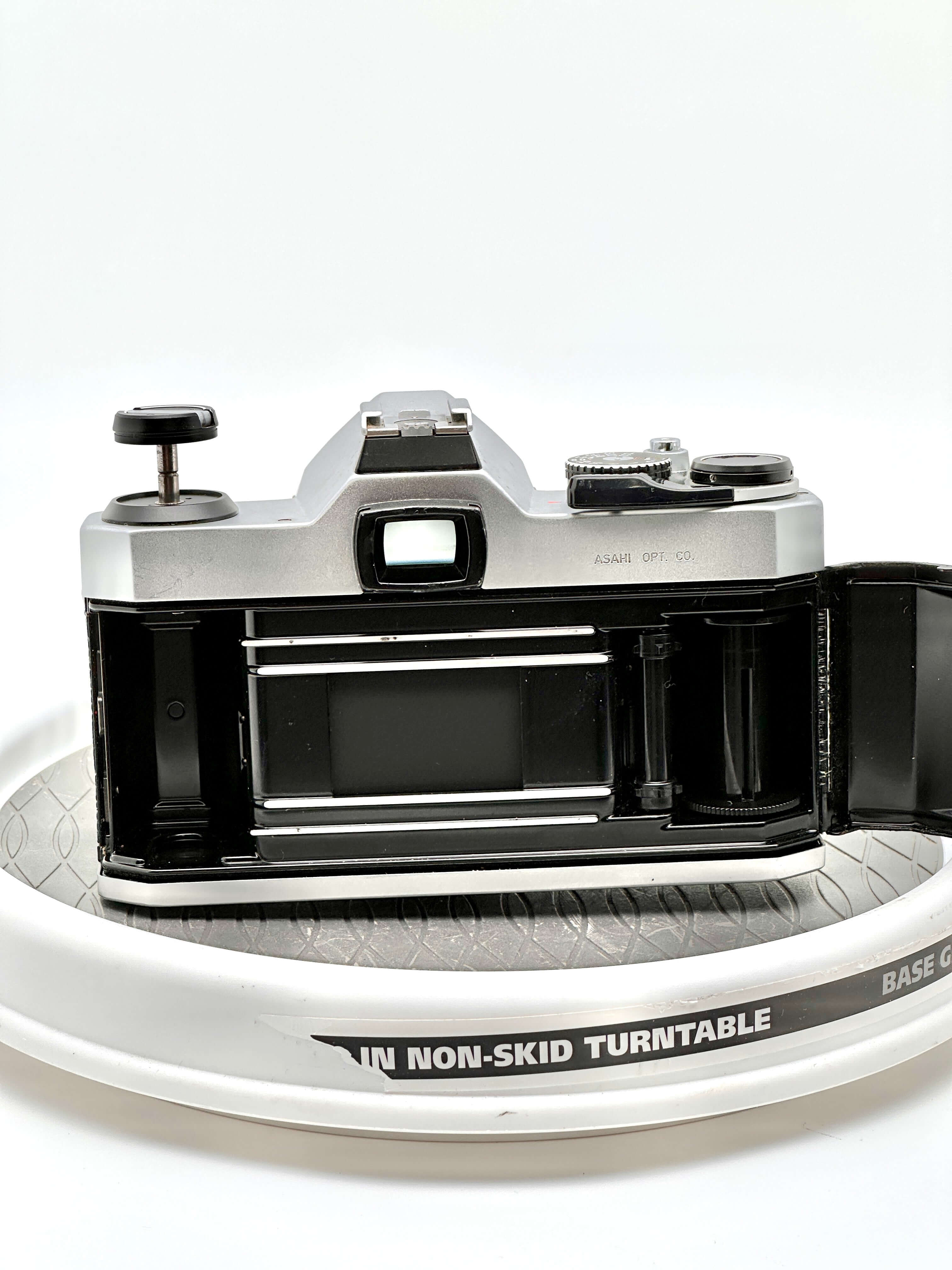 Pentax K1000 film camera rear view showing film compartment and controls on a turntable.
