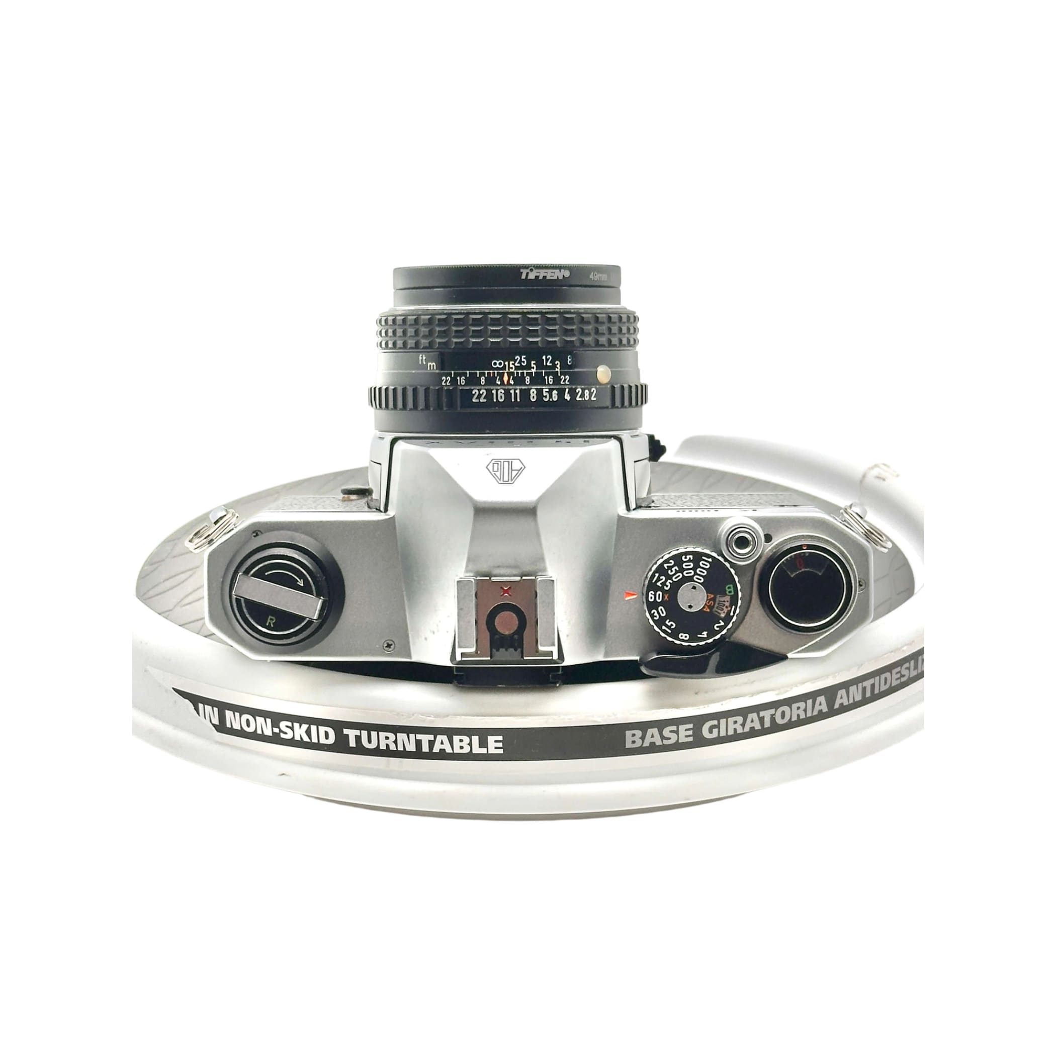 Silver-bodied canon ae-1 film camera with a black tiffen lens mounted on top.