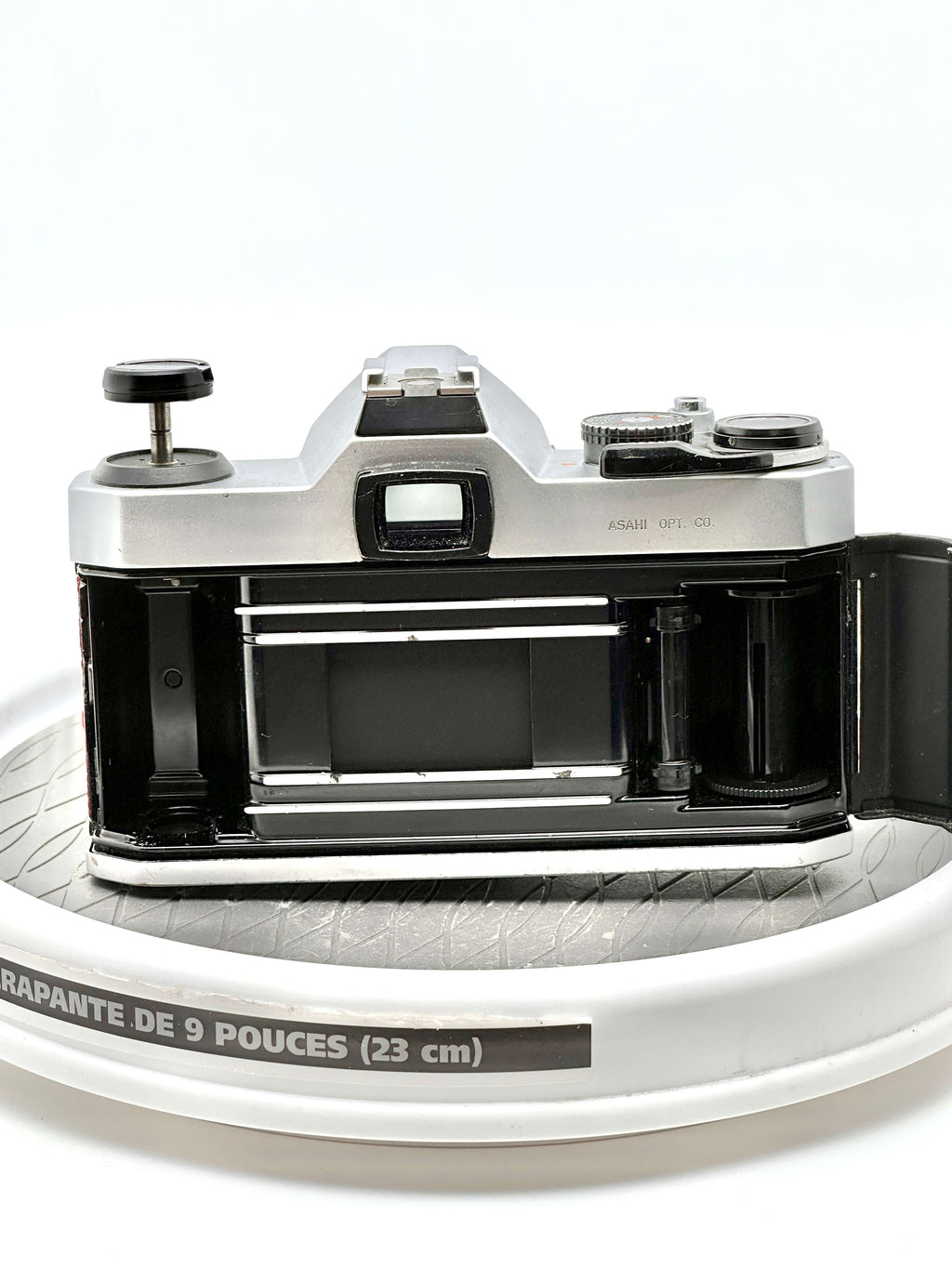 Pentax K1000 35mm film camera rear view showing the film compartment on a round surface.