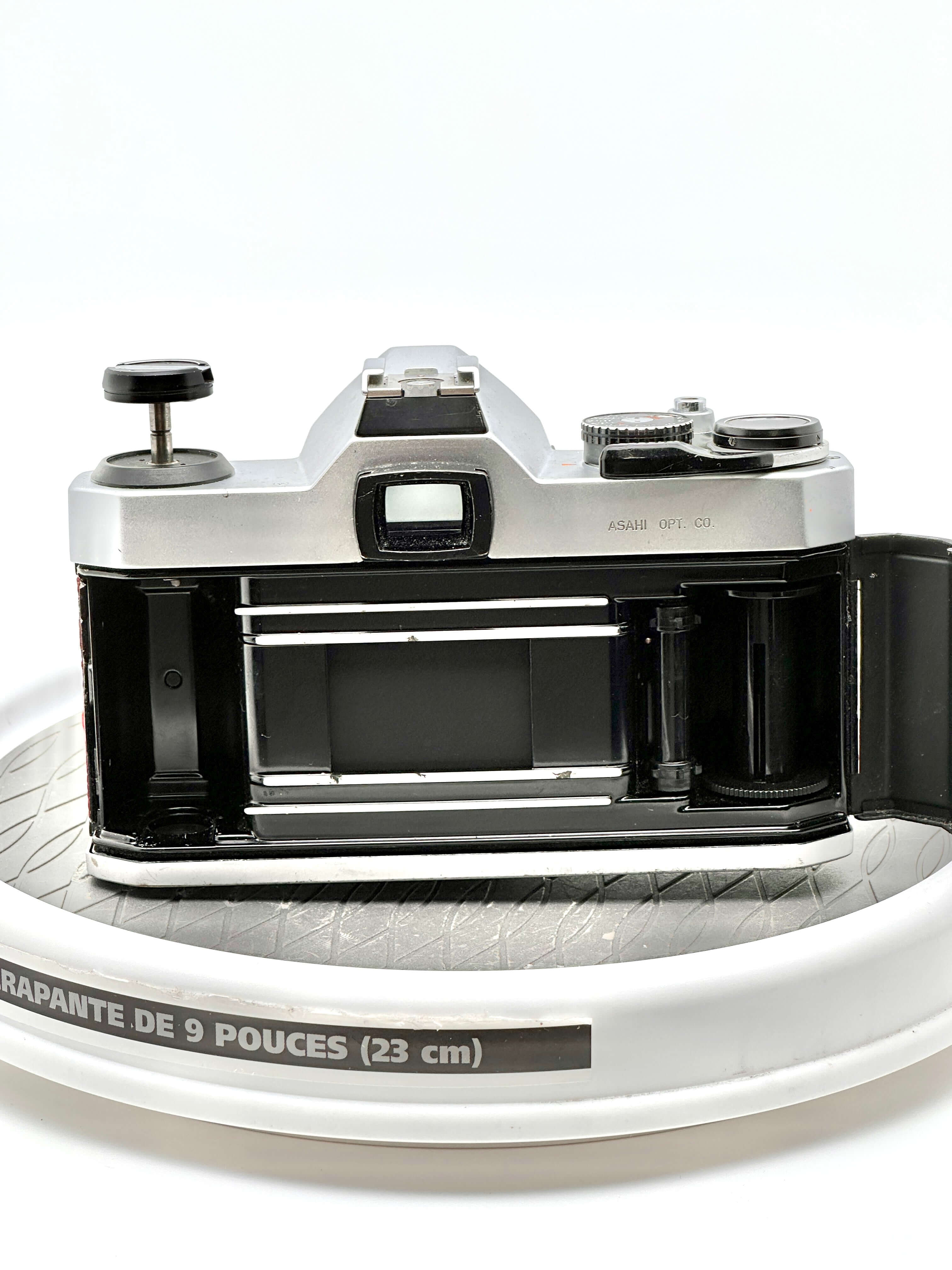 Pentax K1000 35mm film camera rear view showing the film compartment on a round surface.