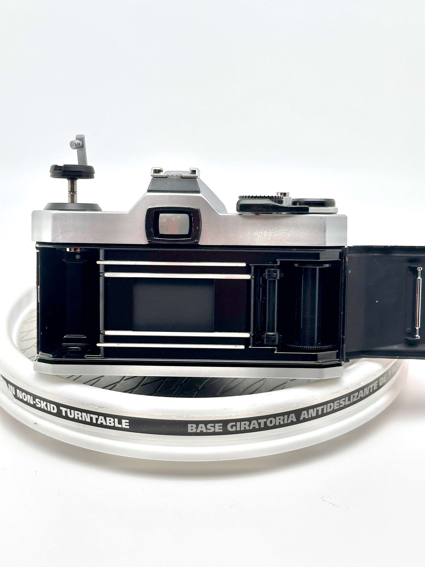 Back view of a Japanese Asahi Pentax K1000 35mm film camera with open film compartment on a non-skid turntable.