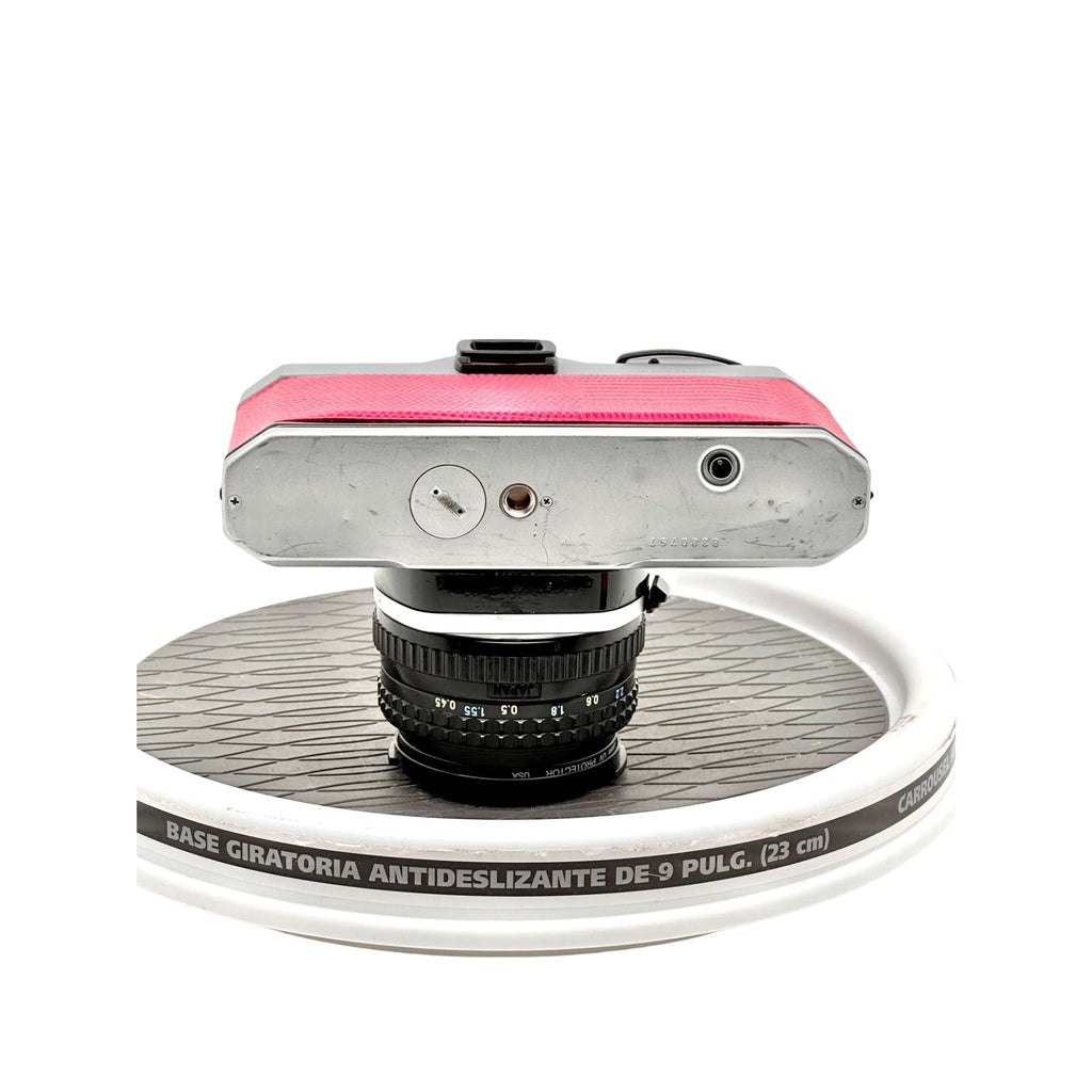 Pink leather-bodied vintage camera with a silver metal top plate and black lens.