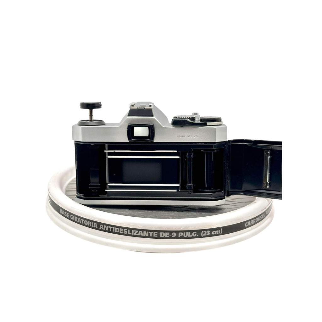 Silver-bodied canon ae-1 film camera with black accents and a visible shutter release button.