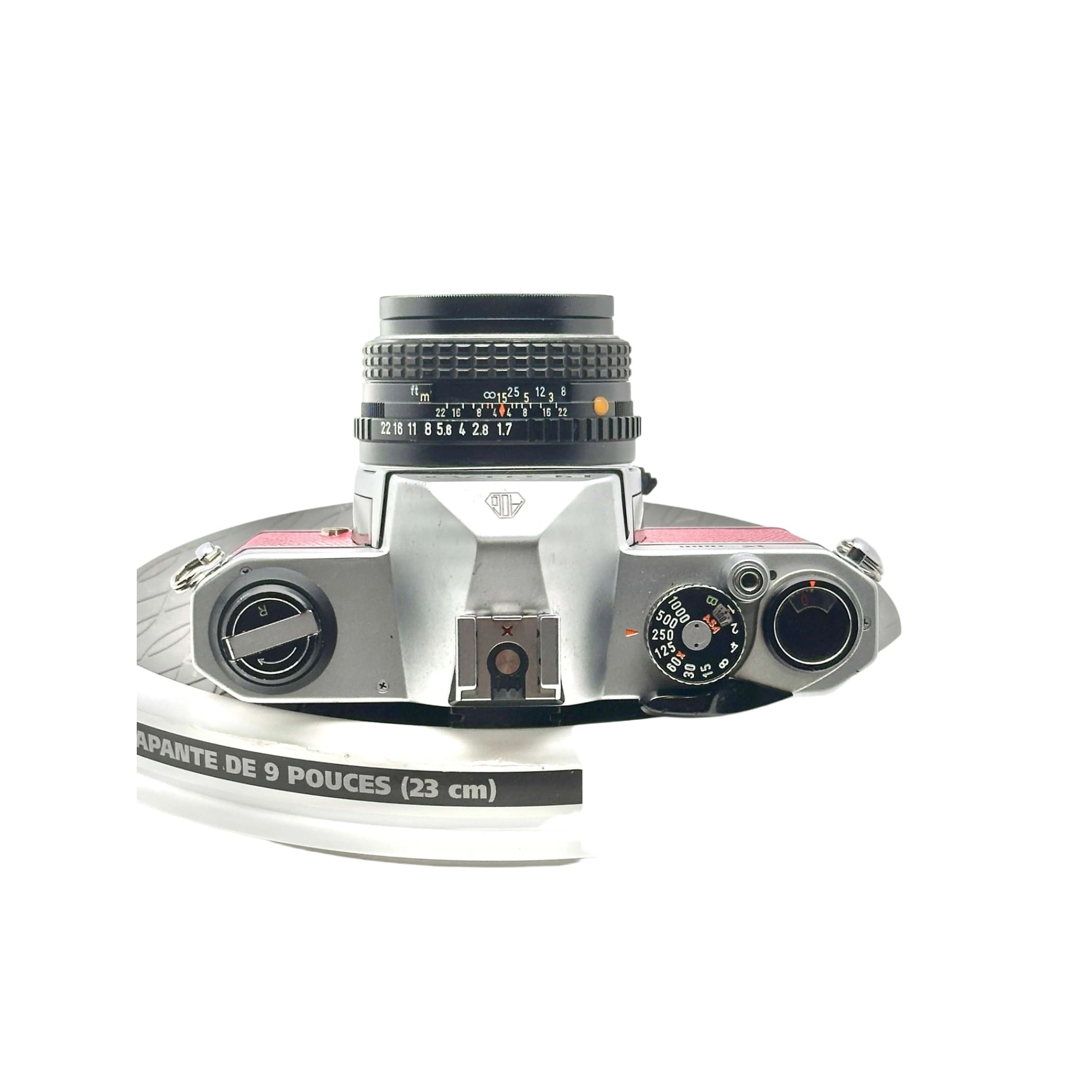 Silver-bodied rangefinder camera with a black lens and pink accents on the top plate.