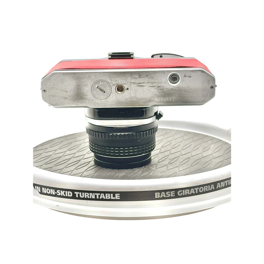 Red and silver vintage camera with a black lens mounted on top.