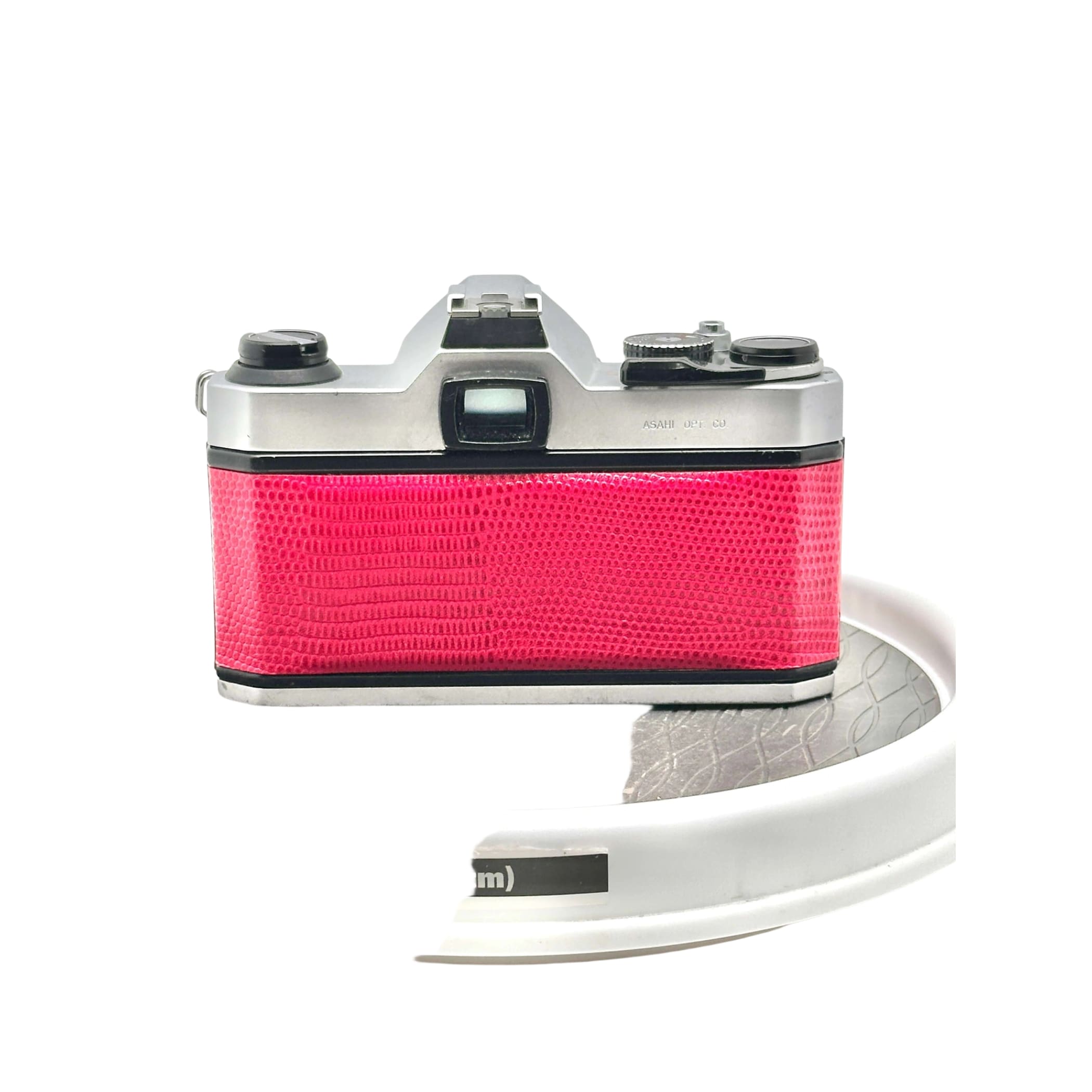 A vibrant pink camera with a textured, reptile-skin patterned body and silver metallic top plate.