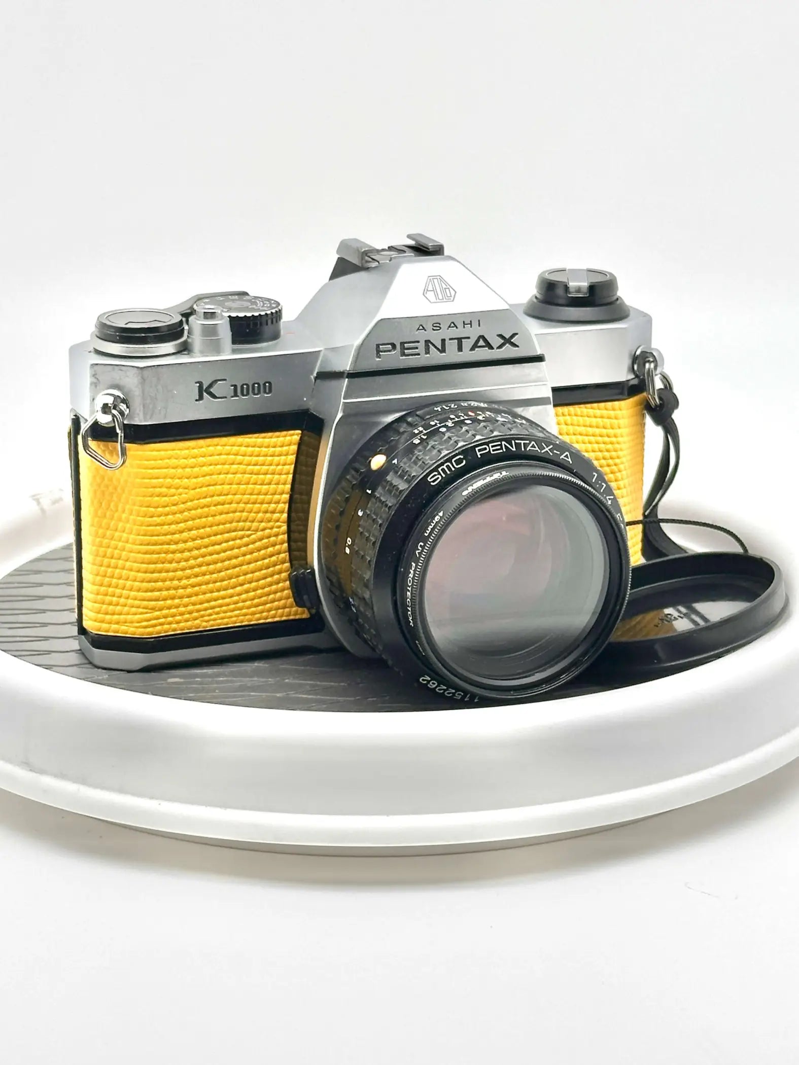 Silver and yellow asahi pentax k1000 film camera with a textured leather grip.