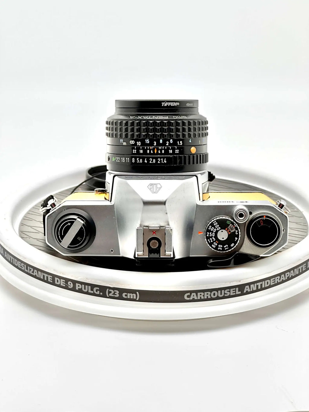 Silver and yellow-bodied canon ae-1 film camera with a black tiffen lens mounted on top.