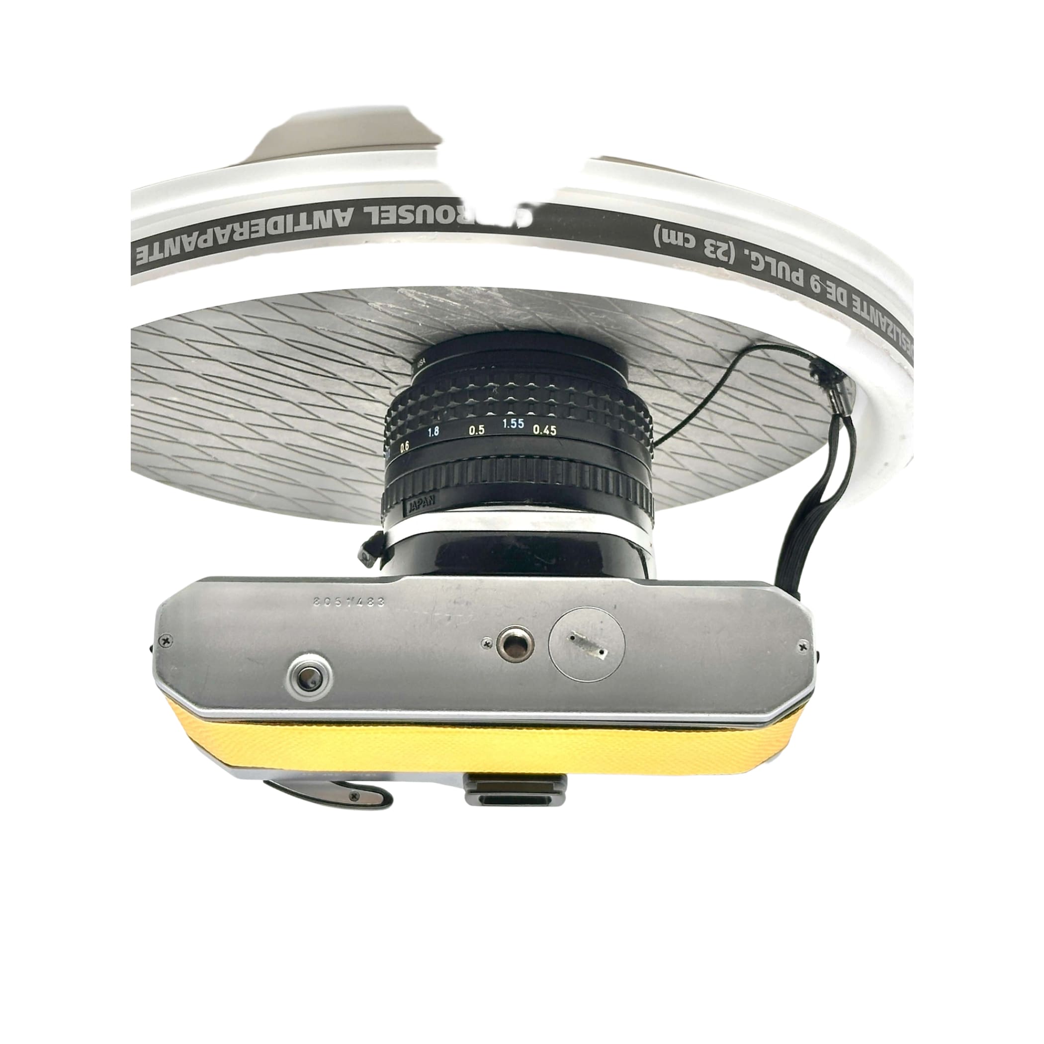 Silver and yellow vintage camera with a black lens mounted beneath a white bicycle wheel rim.