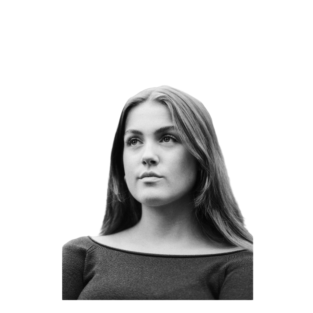 Black-and-white portrait photograph of a woman with long hair wearing an off-the-shoulder knit top.