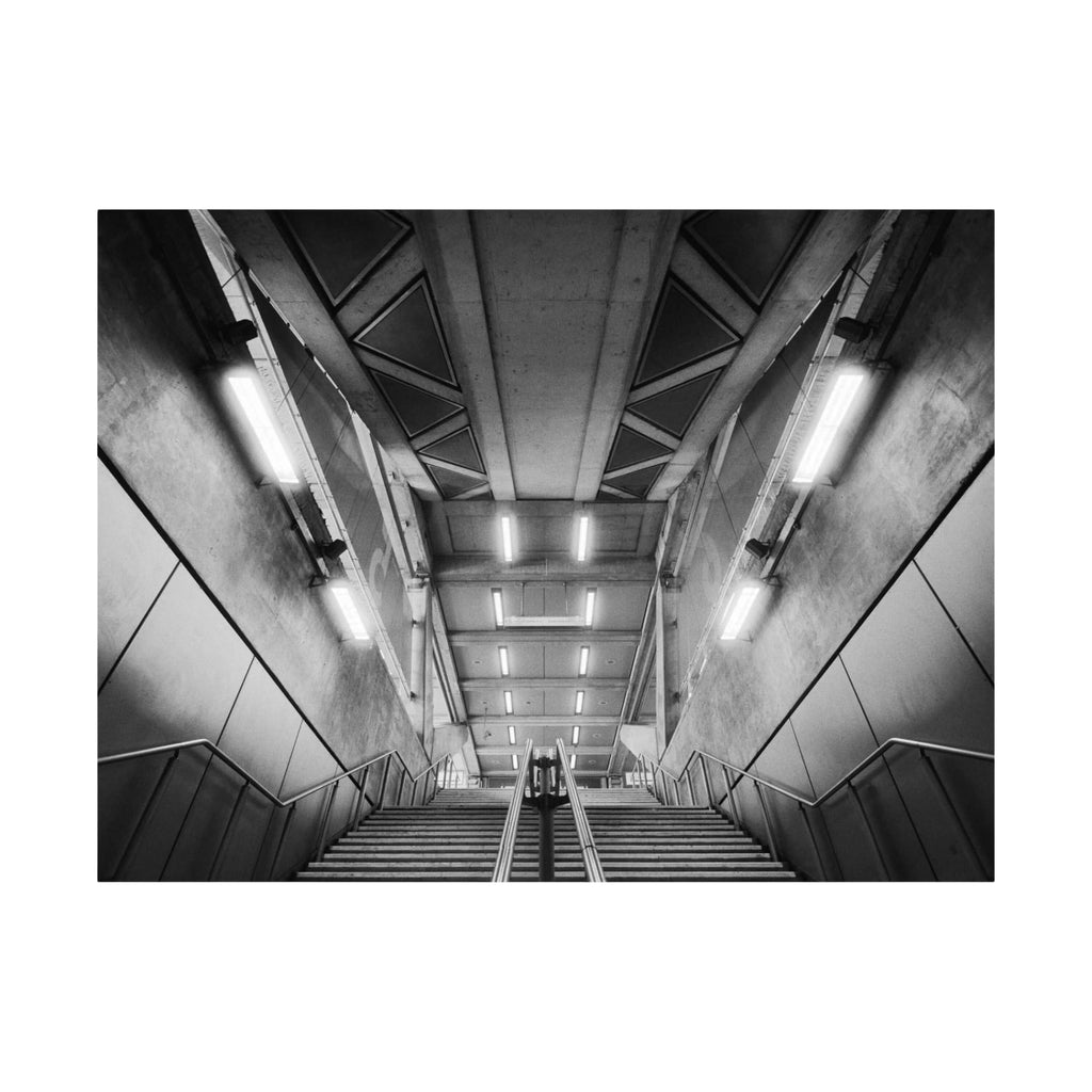 Concrete staircase with metal railings and overhead fluorescent lighting.