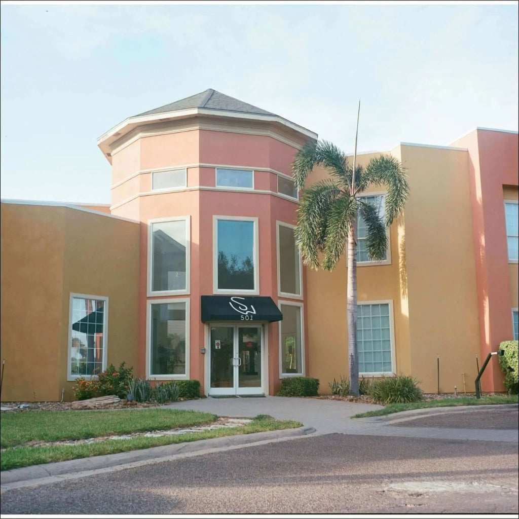 The building features a distinctive pink and orange stucco exterior with white-trimmed windows, a dark awning above the entrance displaying ’501’’ in white lettering.