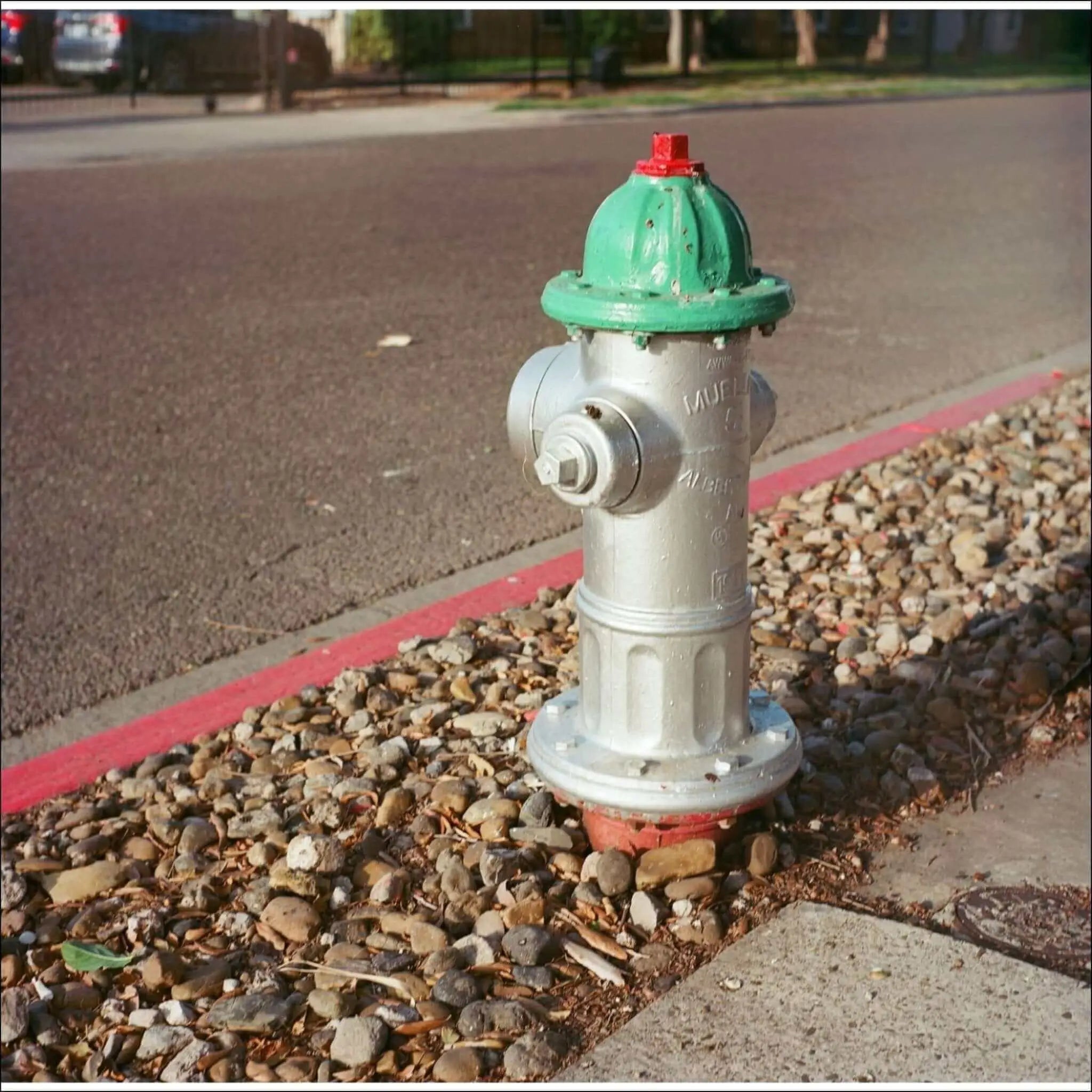 A green and silver fire hydrant with a red cap, featuring embossed markings on its body.