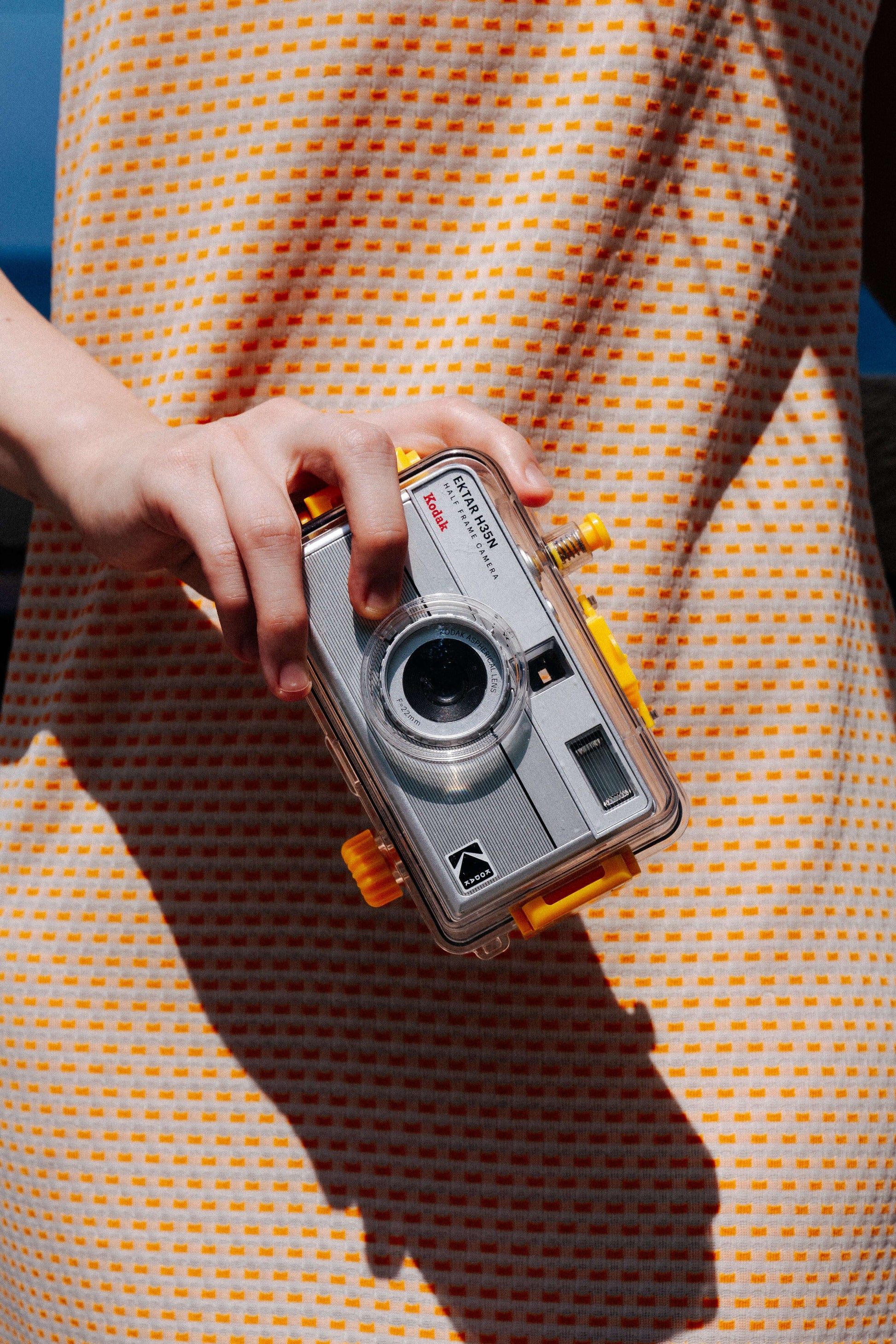 Person holding Kodak Ektar H35N underwater case, showcasing its design against a bright patterned dress.