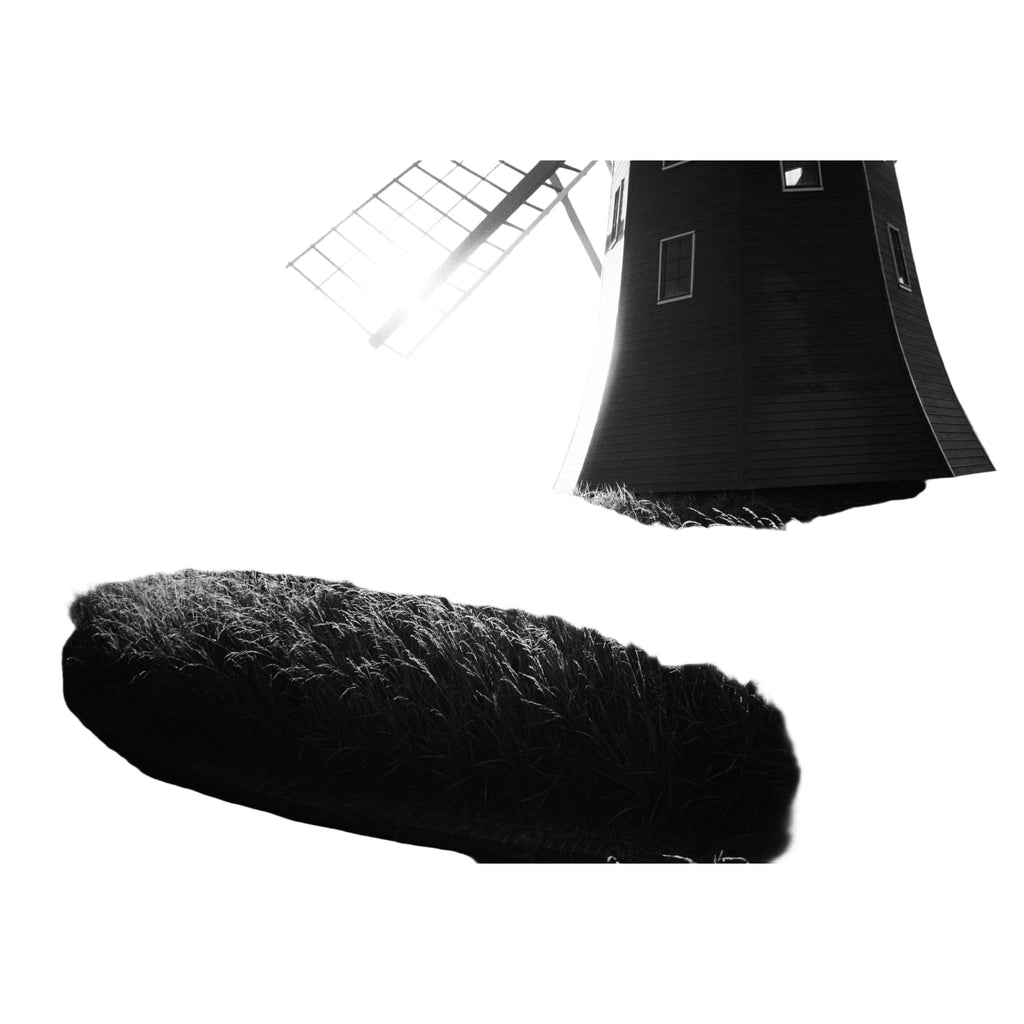 A classic wooden windmill with a dark, weathered body and light-colored lattice blades stands against the sunlit horizon.