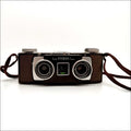 Brown leather-bodied kodak stereo camera with two silver-rimmed lenses and a matching brown strap.