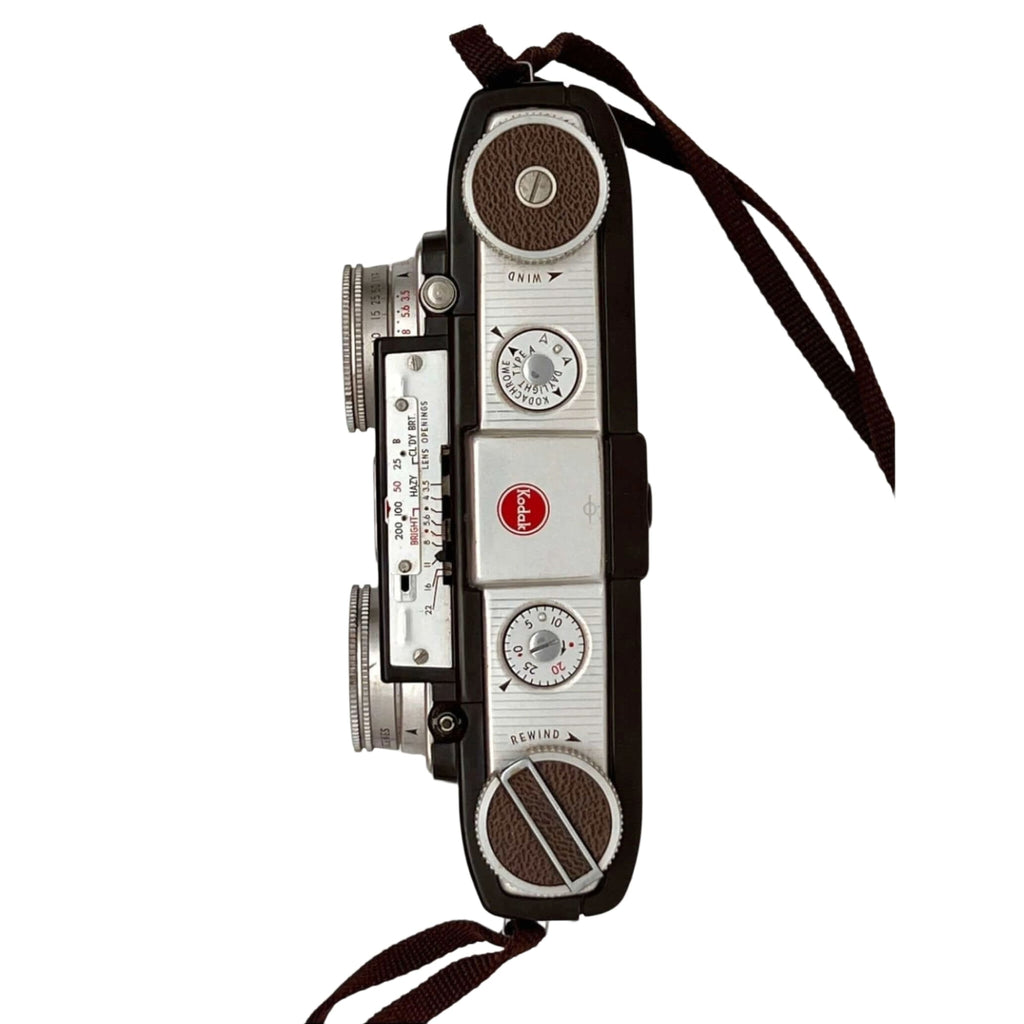 Vintage kodak brownie camera with a silver and black body, brown leather accents on the dials, and classic film rewind and wind knobs.