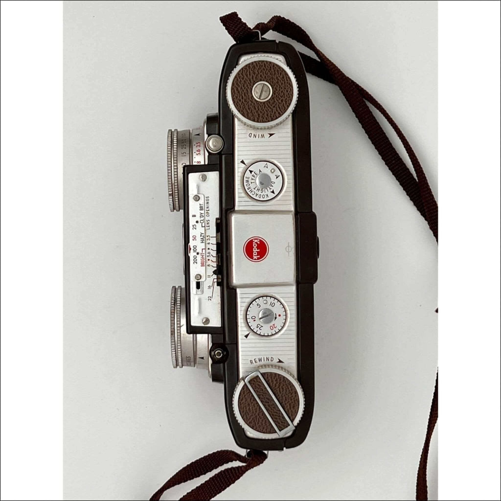 Vintage kodak brownie camera with a silver and black body, brown leather accents on the dials, and classic film rewind and wind knobs.
