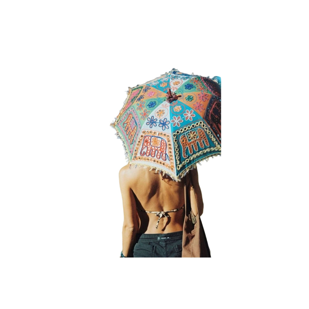 A vibrant, hand-painted indian-style umbrella with intricate floral and elephant motifs in turquoise, orange, red, and blue hues, adorned with decorative fringe along its edges.