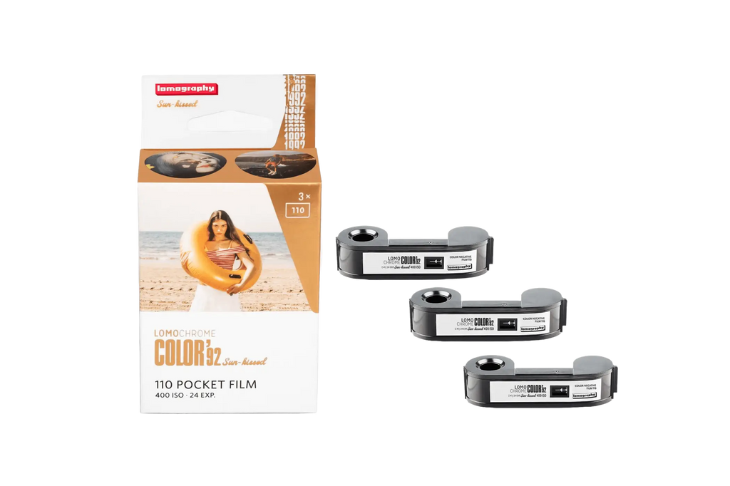 Lomography color 32 sun-kissed 110 pocket film in a white and orange box with three black film reels beside it.