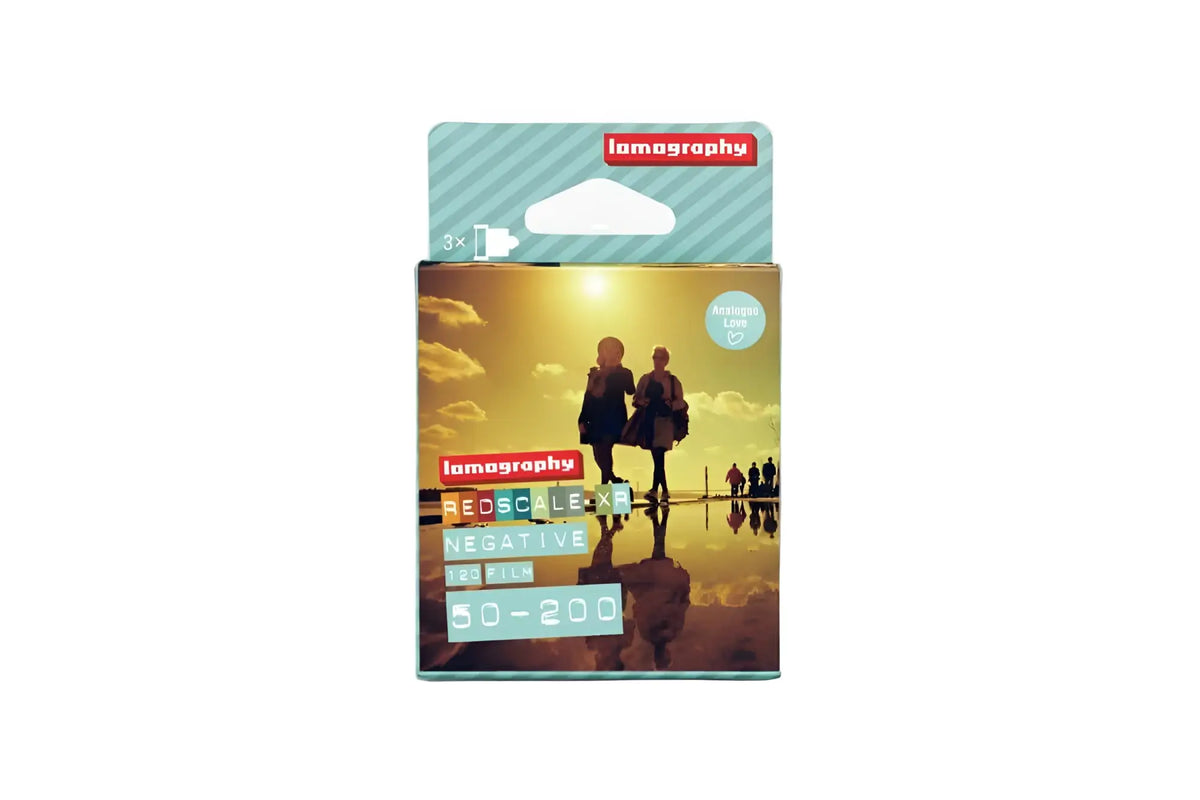 Lomography redscale x negative film pack, featuring a warm sunset image with silhouetted figures on its packaging.