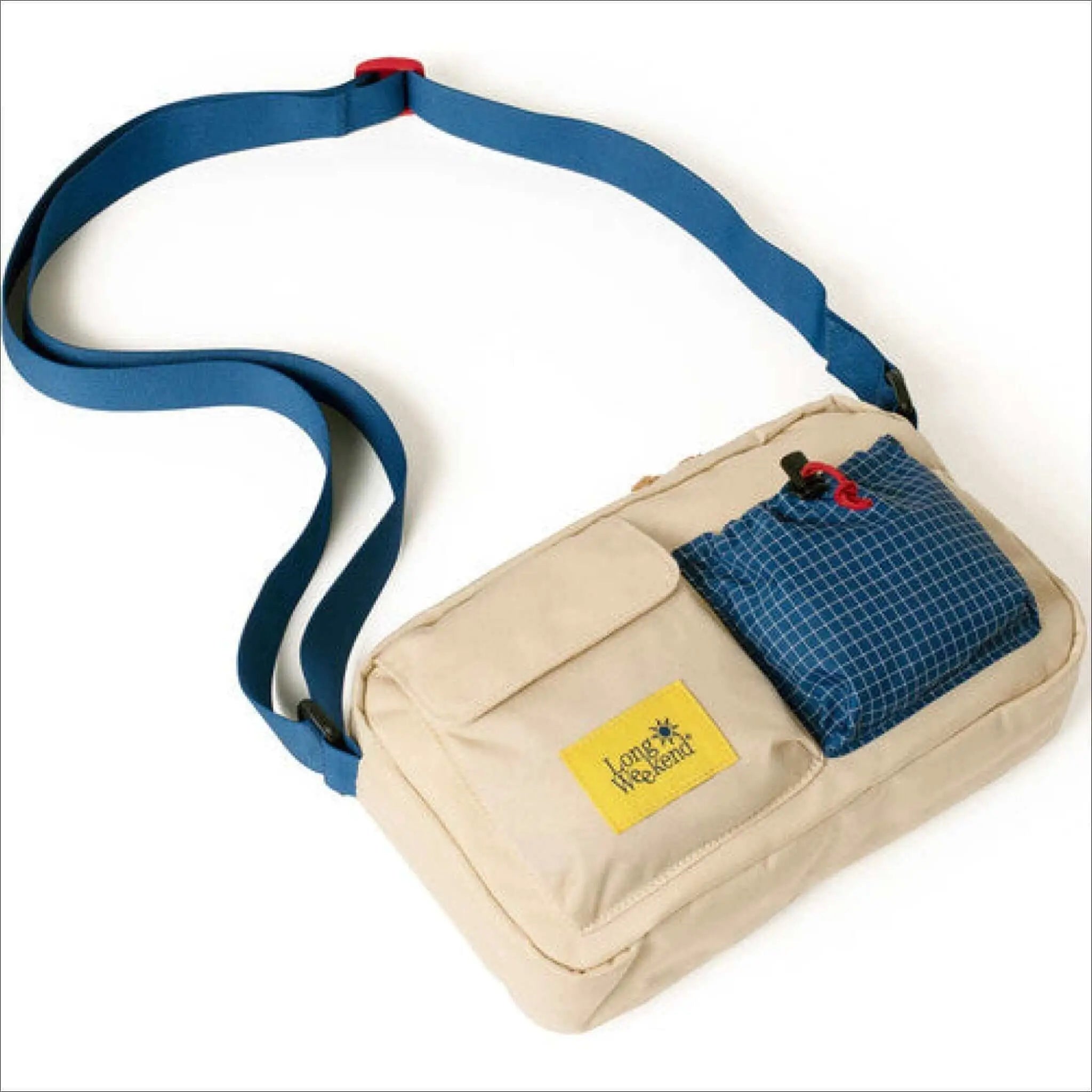 Beige canvas crossbody bag with a blue grid-patterned pocket and matching adjustable strap.