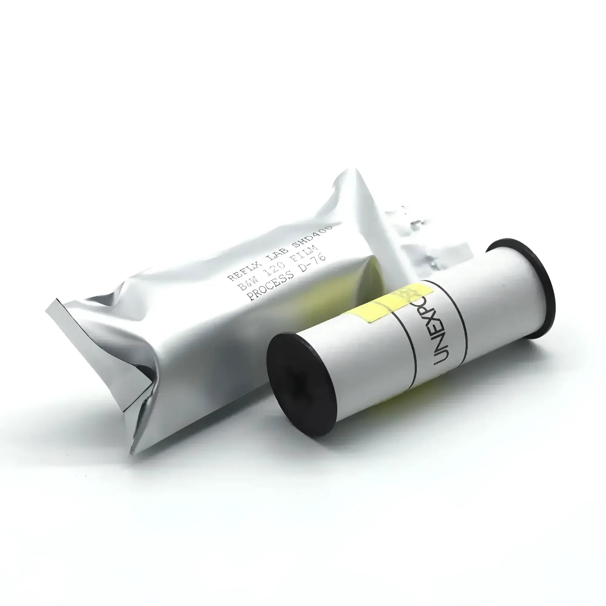 A white cylindrical film canister with black ends and a yellow label, branded ’uniexpo,’ resting beside its silver foil packaging.