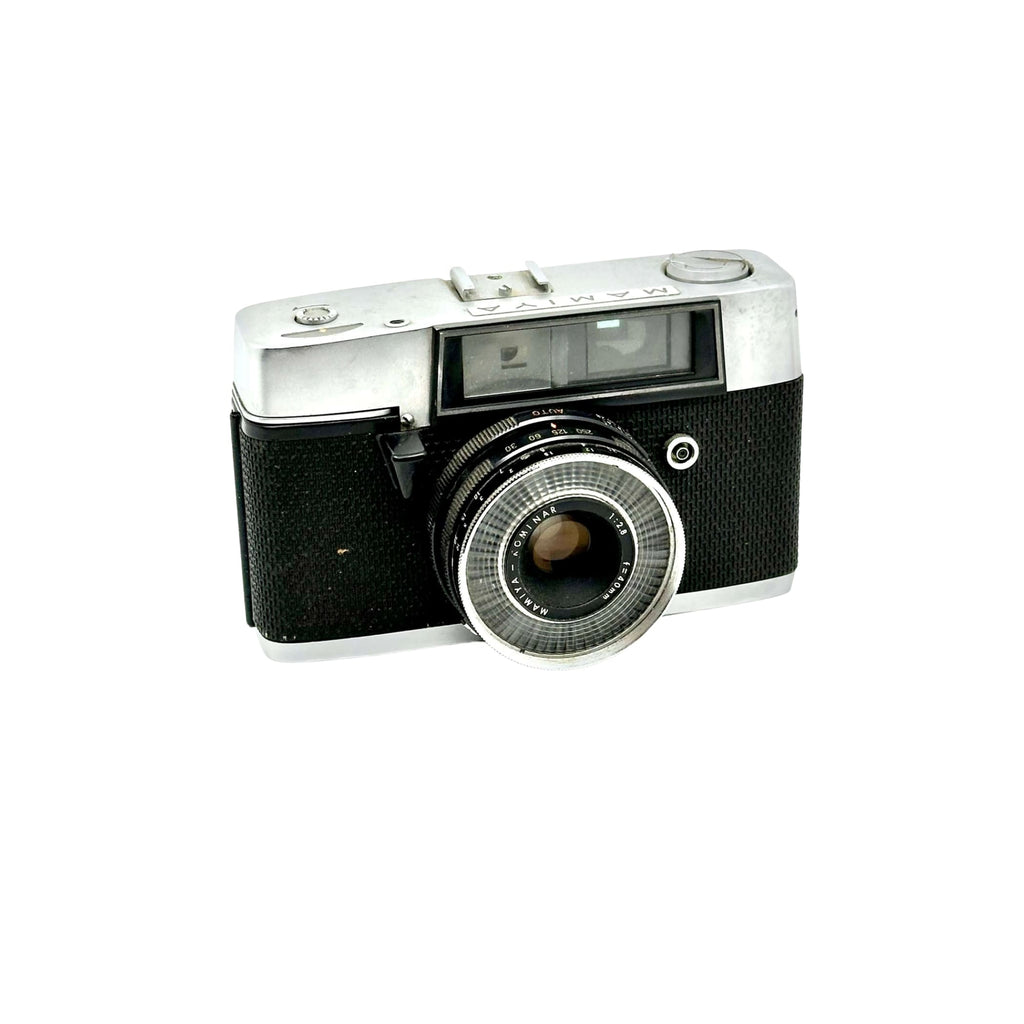 Silver and black mamiya film camera with a textured grip and chrome lens ring.