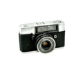 Silver and black mamiya film camera with a textured grip and chrome lens ring.