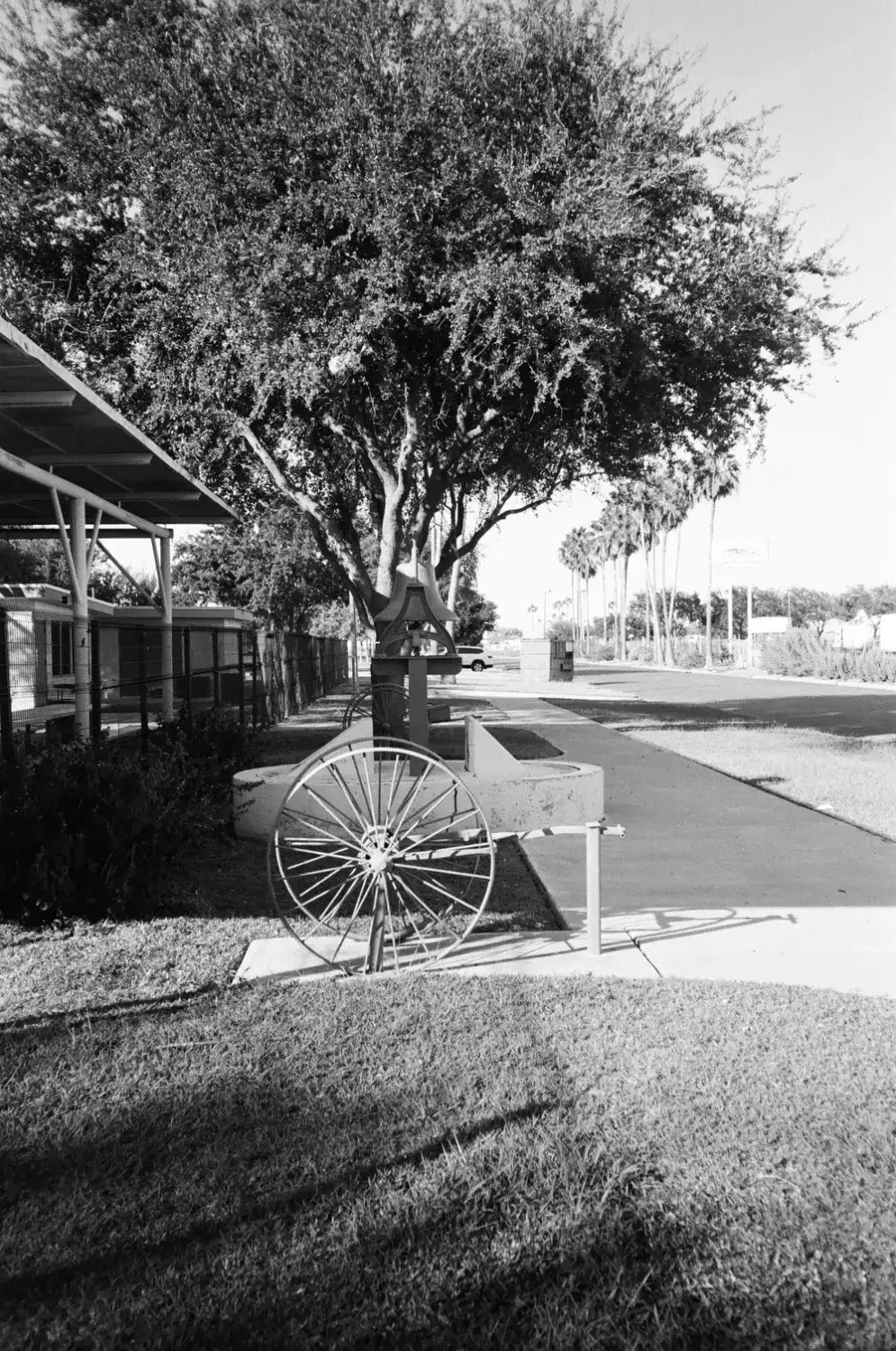 Rustic cart wheel with metallic spokes on wooden axle, shot on Catlabs x Film Kodak Tri-X 400 Cinestill Bwxx 250