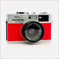 Red textured body with silver top and lens mount, featuring an olympus 35 rc camera equipped with a zuiko 42mm f/1.8 lens.