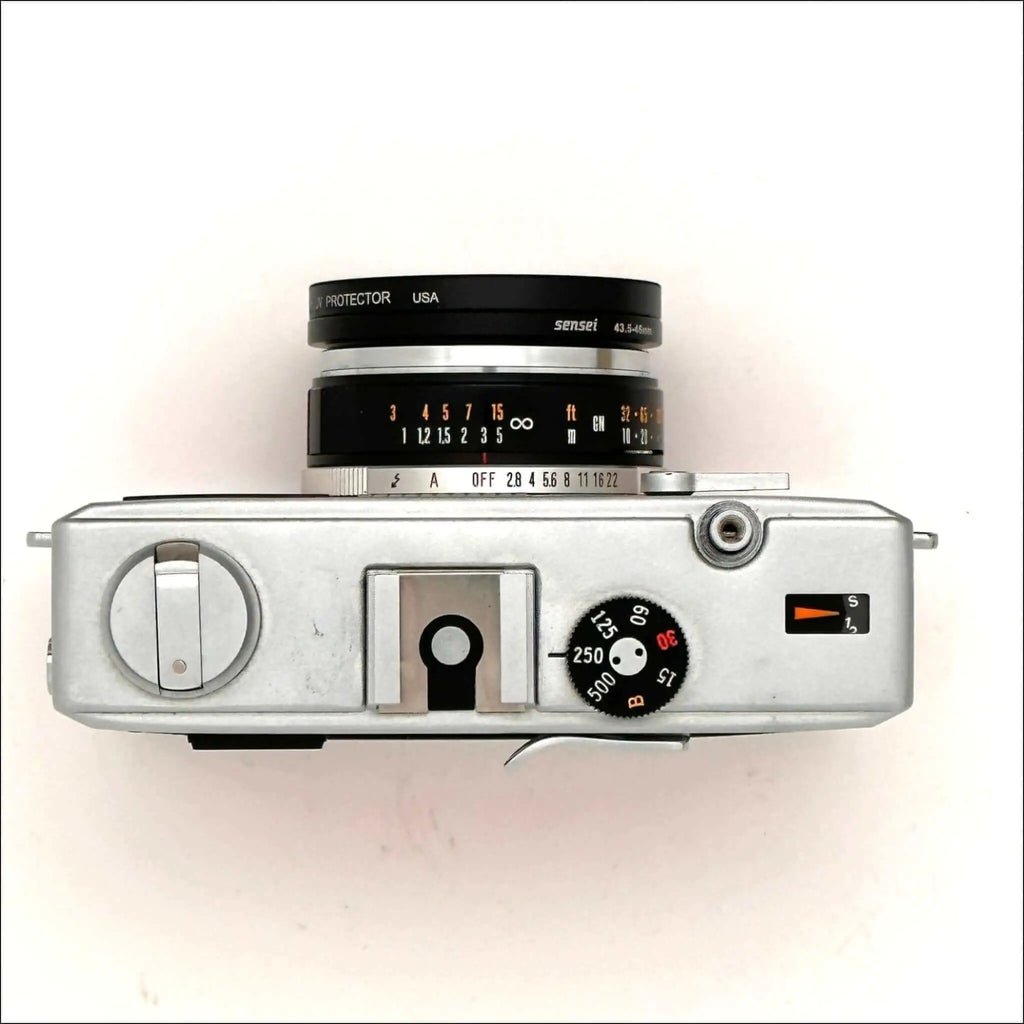 Silver-bodied rangefinder camera with a black and silver lens marked ’sensei 43-5.6mm’ mounted on top, featuring manual focus dials and shutter speed settings visible on its side panel.