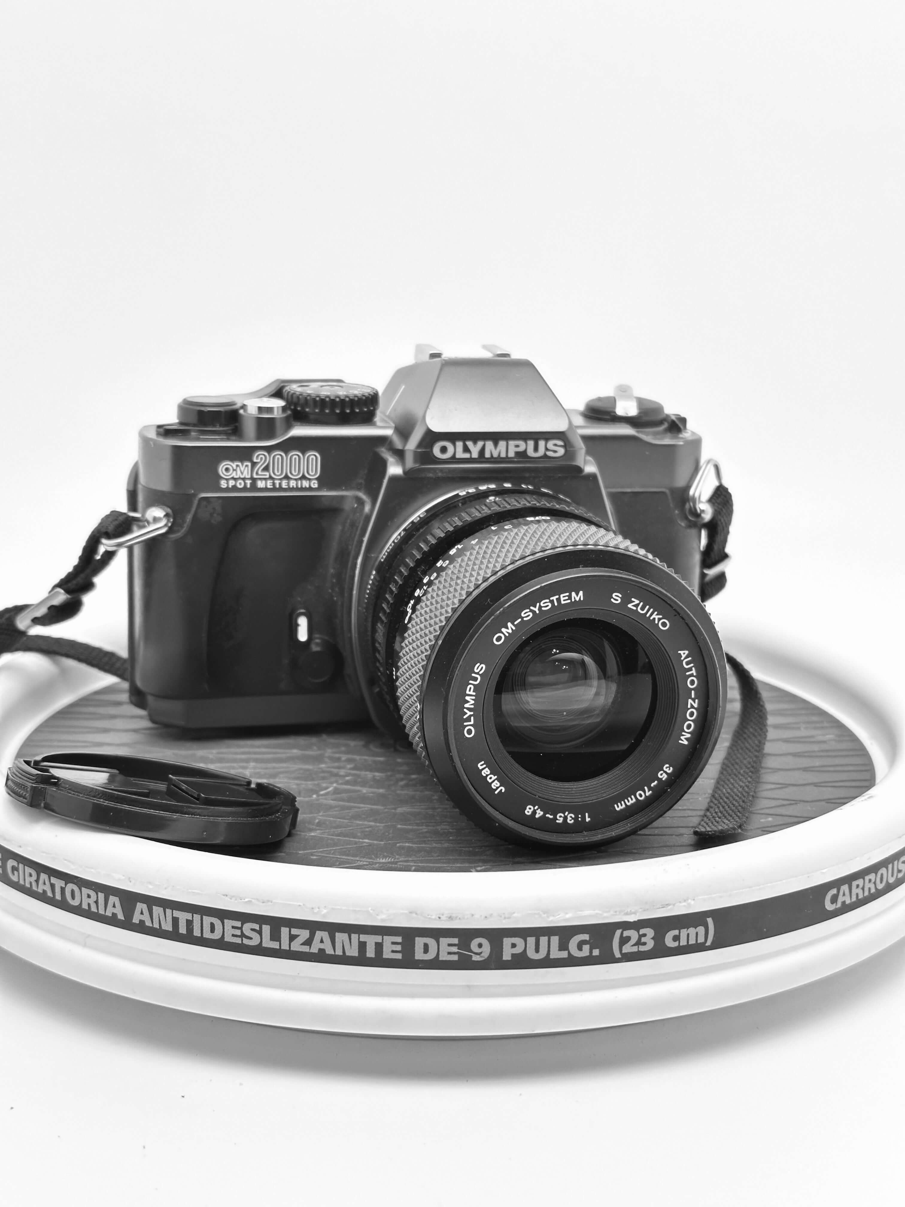 Olympus OM 2000 film camera with 35-70mm lens on a round surface, showcasing its vintage appeal and design.