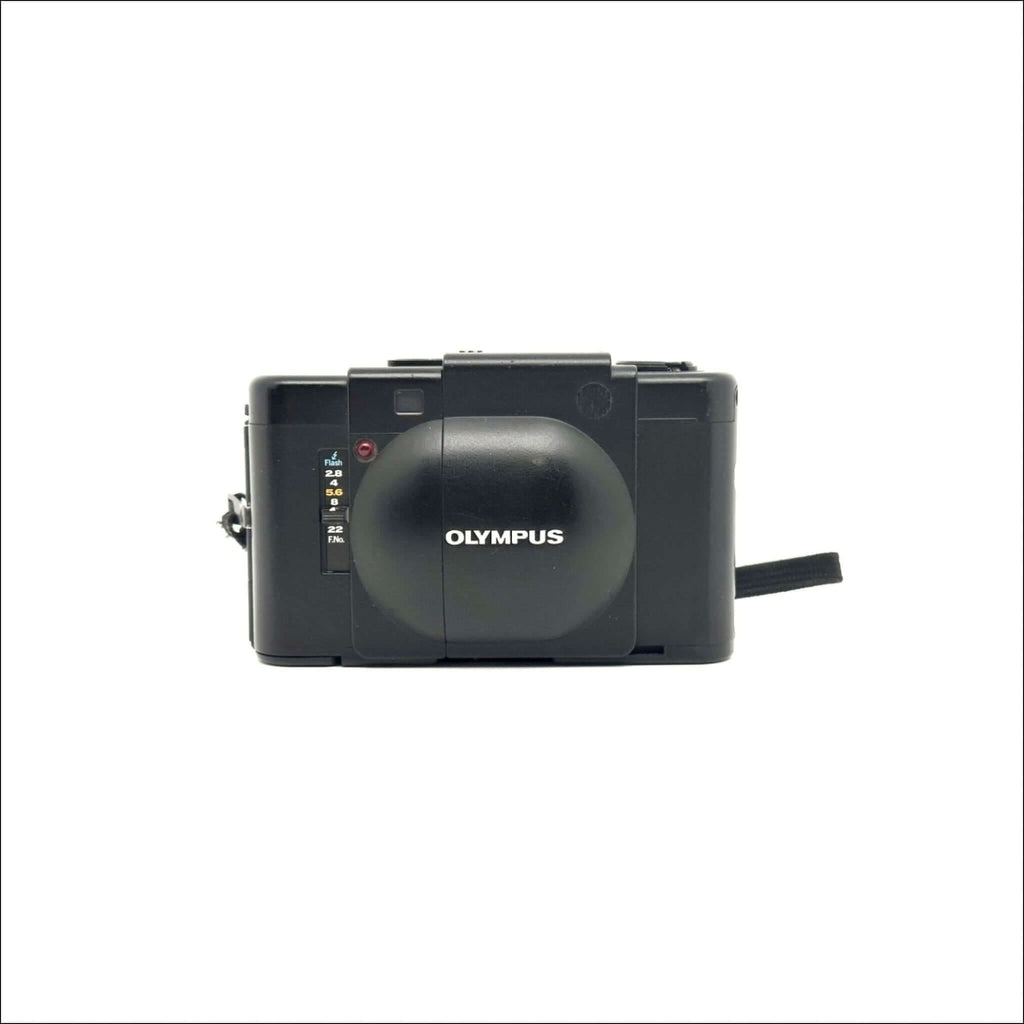 Black olympus camera with a rounded lens cover and manual focus dial.