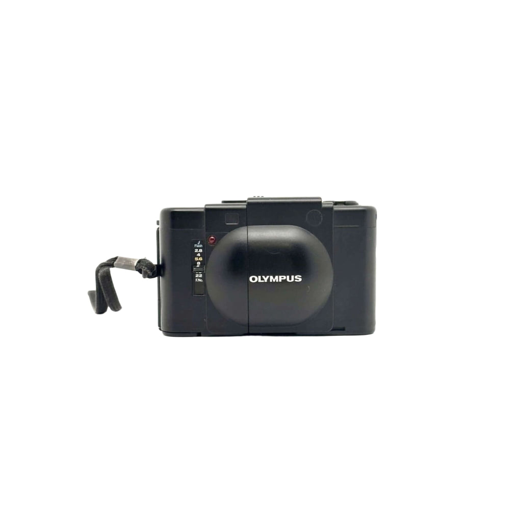 Black olympus digital camera with a rounded lens cover and a textured grip.