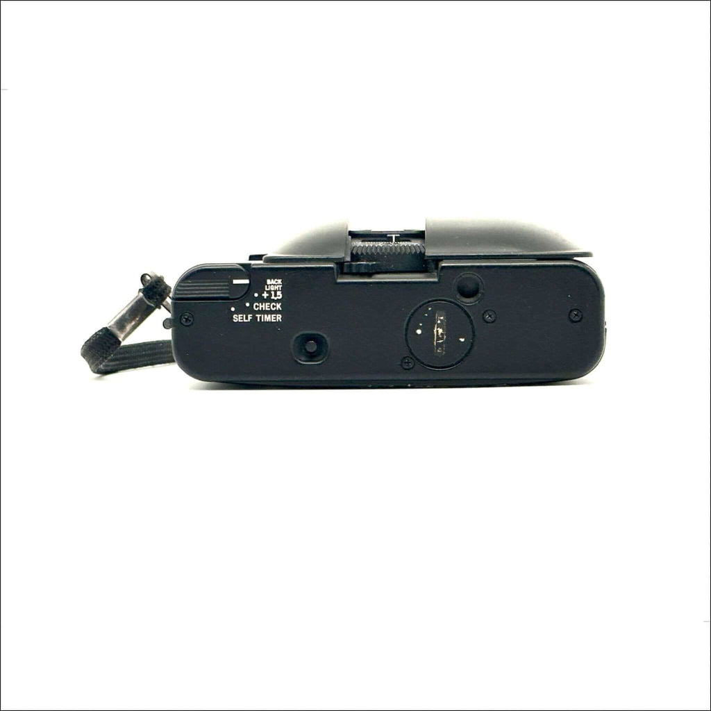 Black fujifilm compact camera with a textured grip and visible control dials.
