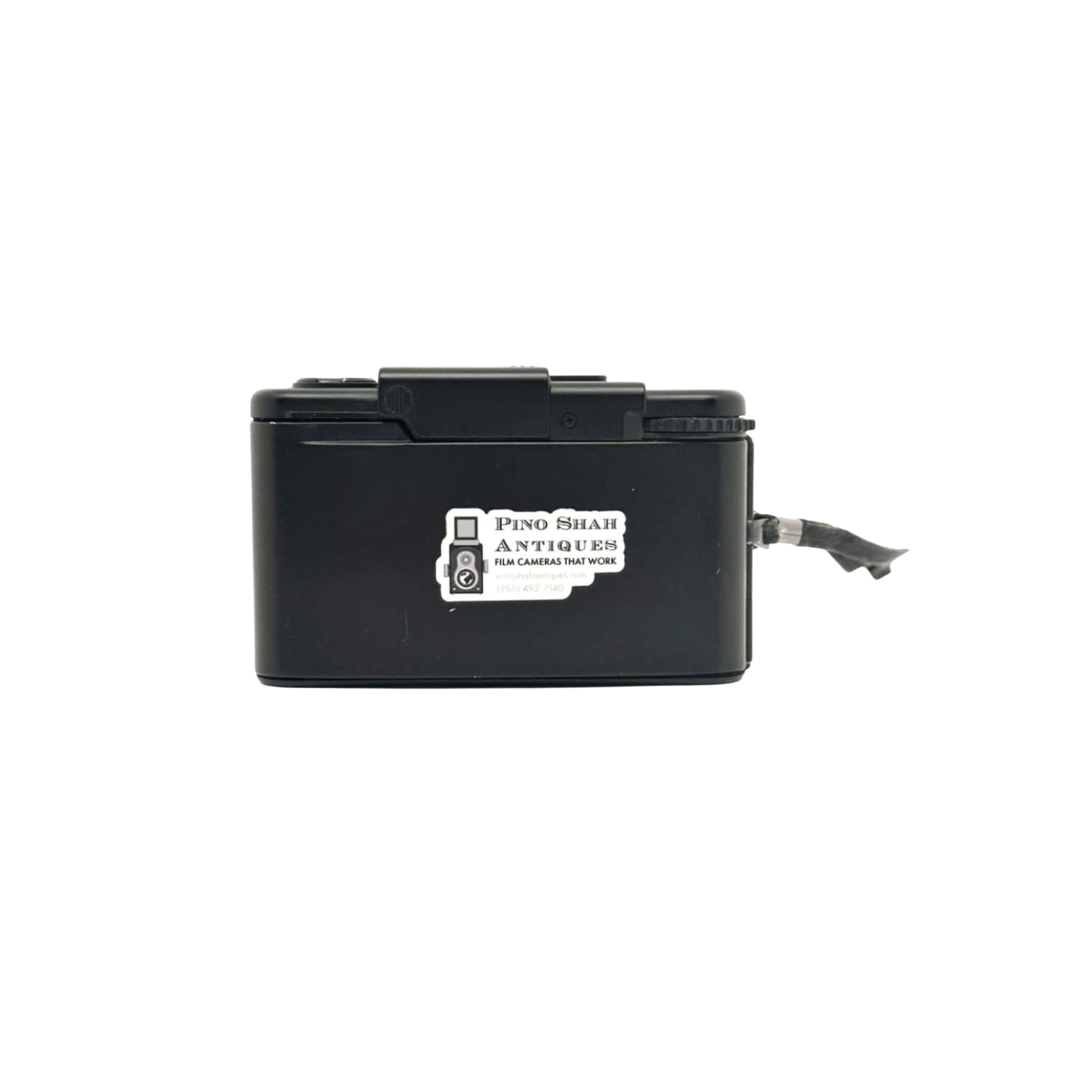 Black plastic box camera with a white sticker reading ’pino shar antiques film cameras that work’ on its side.
