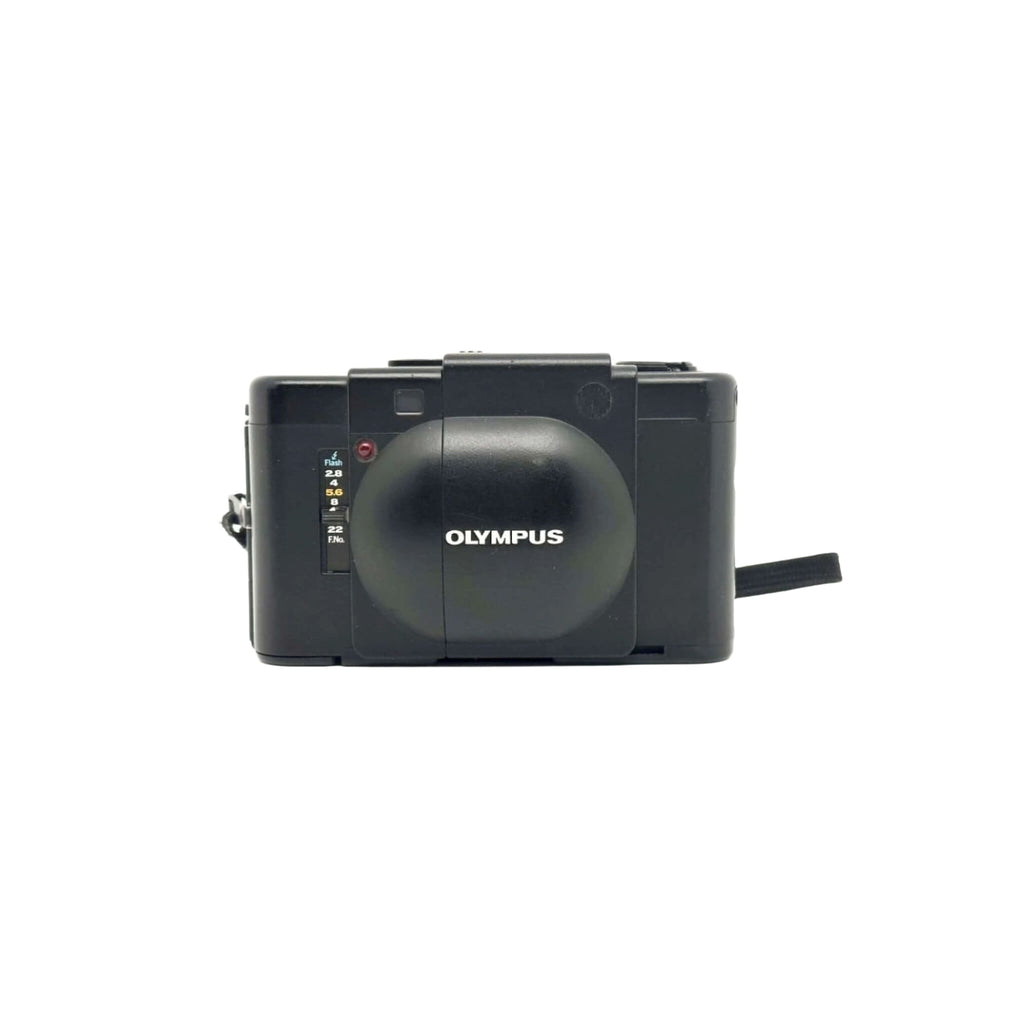 Black olympus camera with a rounded lens cover and manual focus dial.